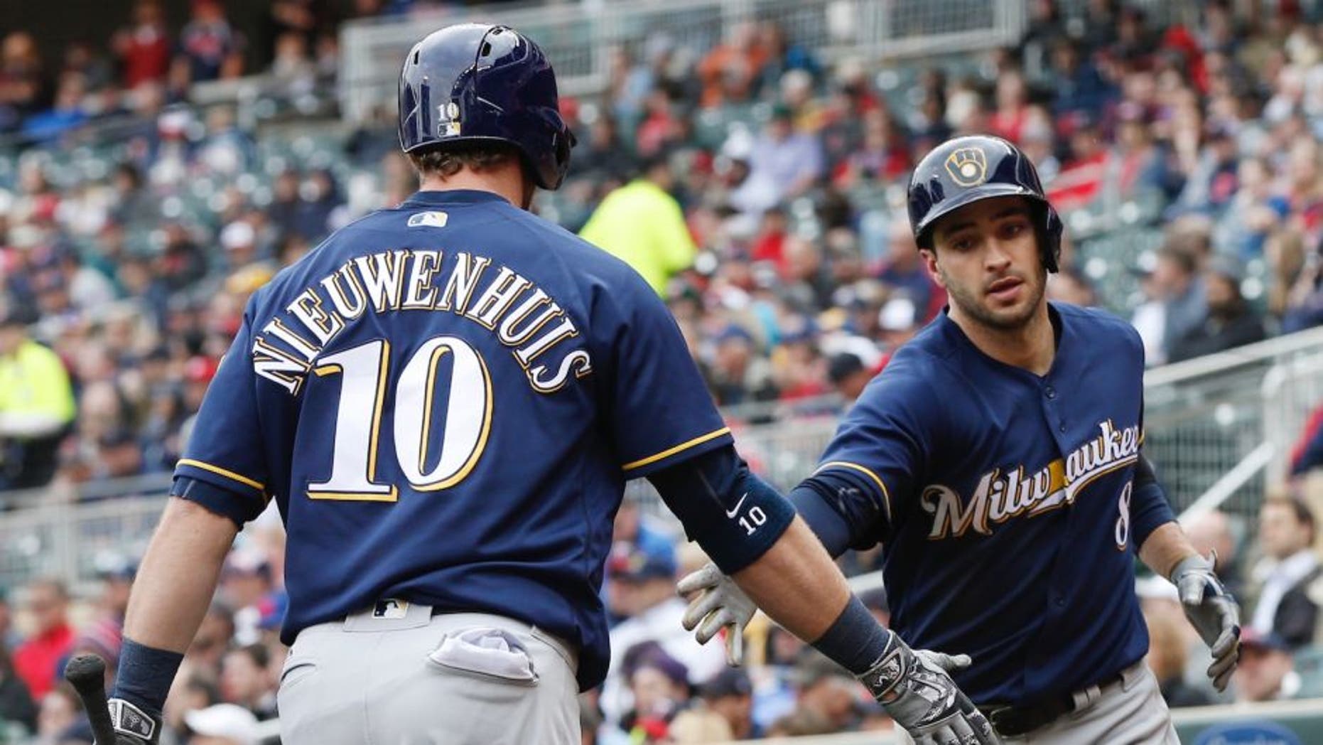 Milwaukee Brewers' Ryan Braun, right, is congratulated by Kirk Nieuwenhuis after scoring on a sacrifice fly by Chris Carter off Minnesota Twins pitcher Ervin Santana, right, in the fifth inning of a baseball game Tuesday, April 19, 2016, in Minneapolis. (AP Photo/Jim Mone)