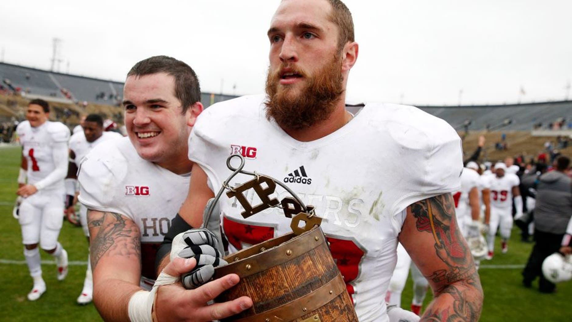 Nov 28, 2015; West Lafayette, IN, USA; Indiana Hoosiers center Jake Reed (50) and offensive tackle Jason Spriggs (78) walk off the field carrying the Old Oaken Bucket after the victory against the Purdue Boilermakers at Ross Ade Stadium. Indiana defeats Purdue 54-36. Mandatory Credit: Brian Spurlock-USA TODAY Sports
