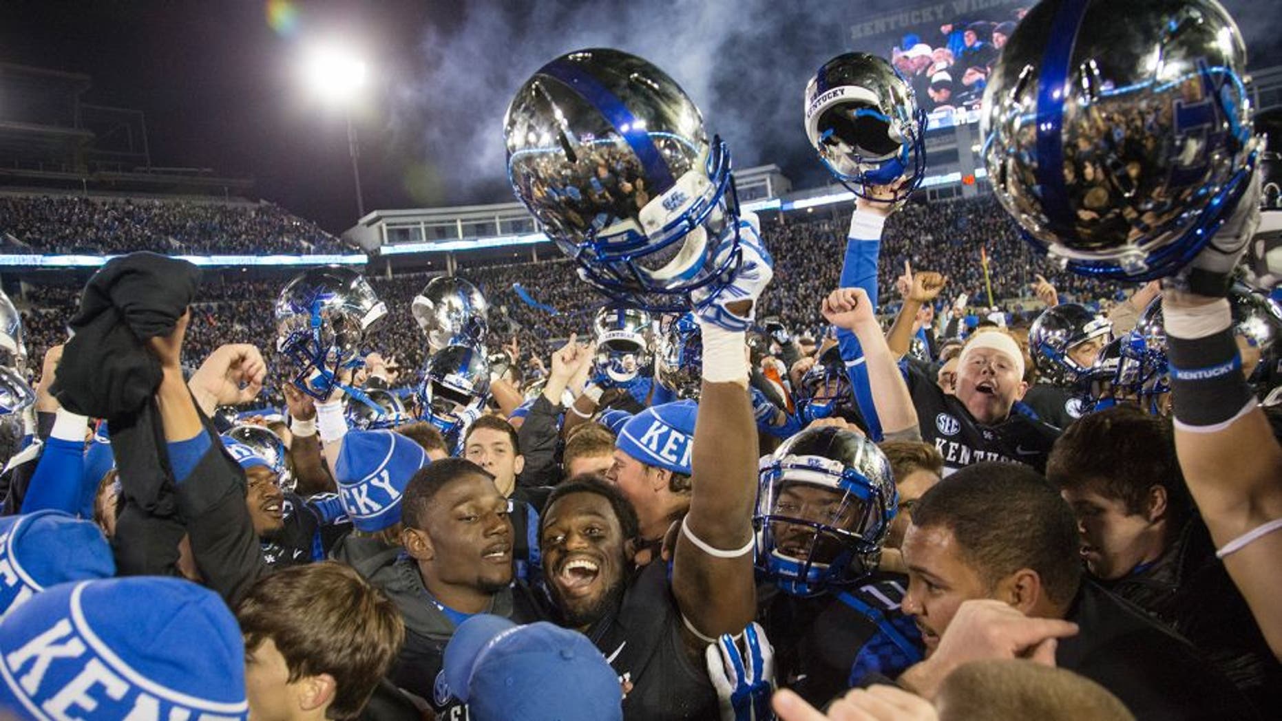 Fans and Kentucky players celebrate together on the field after Kentucky defeated South Carolina 45-38 in an NCAA college football game in Lexington, Ky., Saturday, Oct. 4, 2014. (AP Photo/David Stephenson)