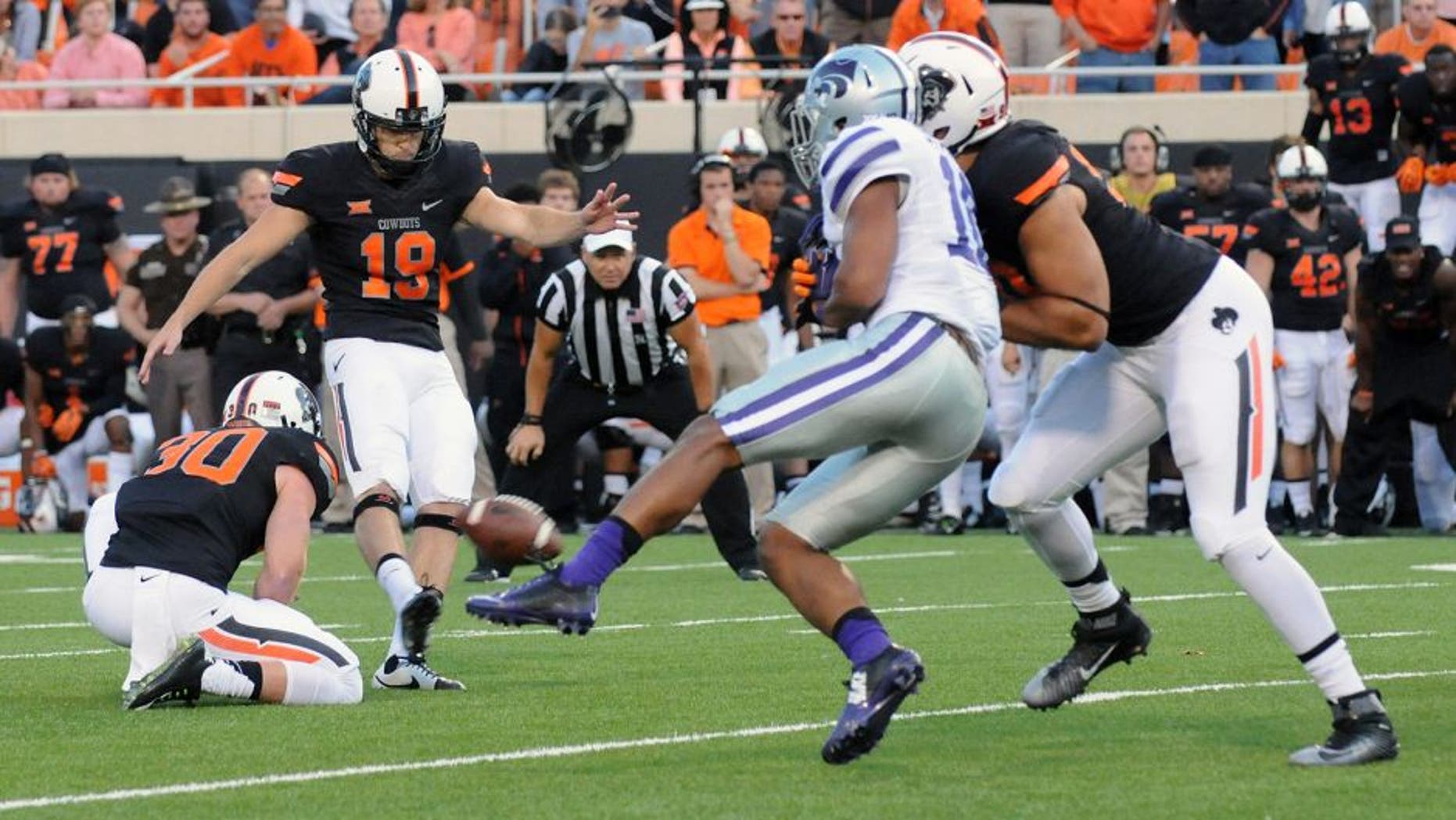 Oklahoma State defensive end Trace Clark, right, defends against Kansas State defensive back Donnie Starks, center right, while Oklahoma State kicker Ben Grogan, center left, kicks the winning field goal held by Oklahoma State holder Bryant Reber, left, during the final seconds of an NCAA football game in Stillwater, Okla., Saturday, Oct. 3, 2015. (AP Photo/Brody Schmidt)