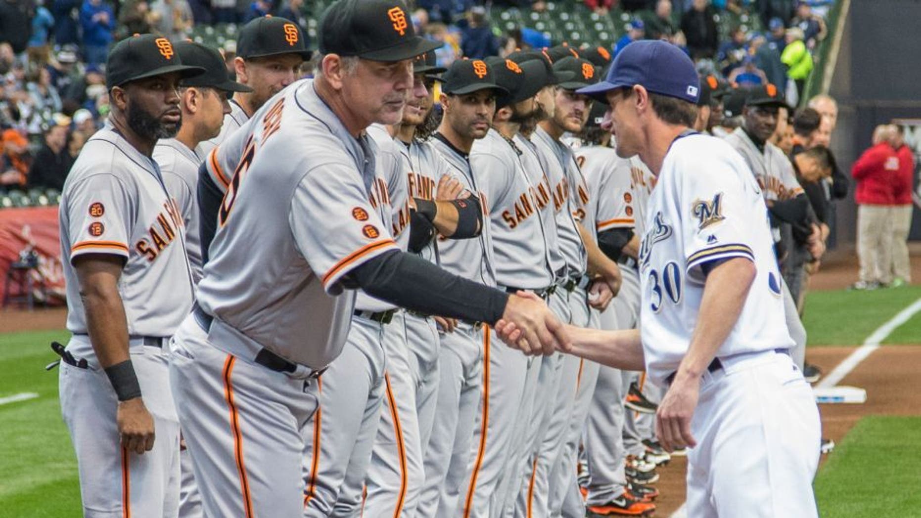 San Fransisco Giants' manager Bruce Bochy, front left, shakes hands with Milwaukee Brewers' manager Craig Counsell before the start of the opening day game.