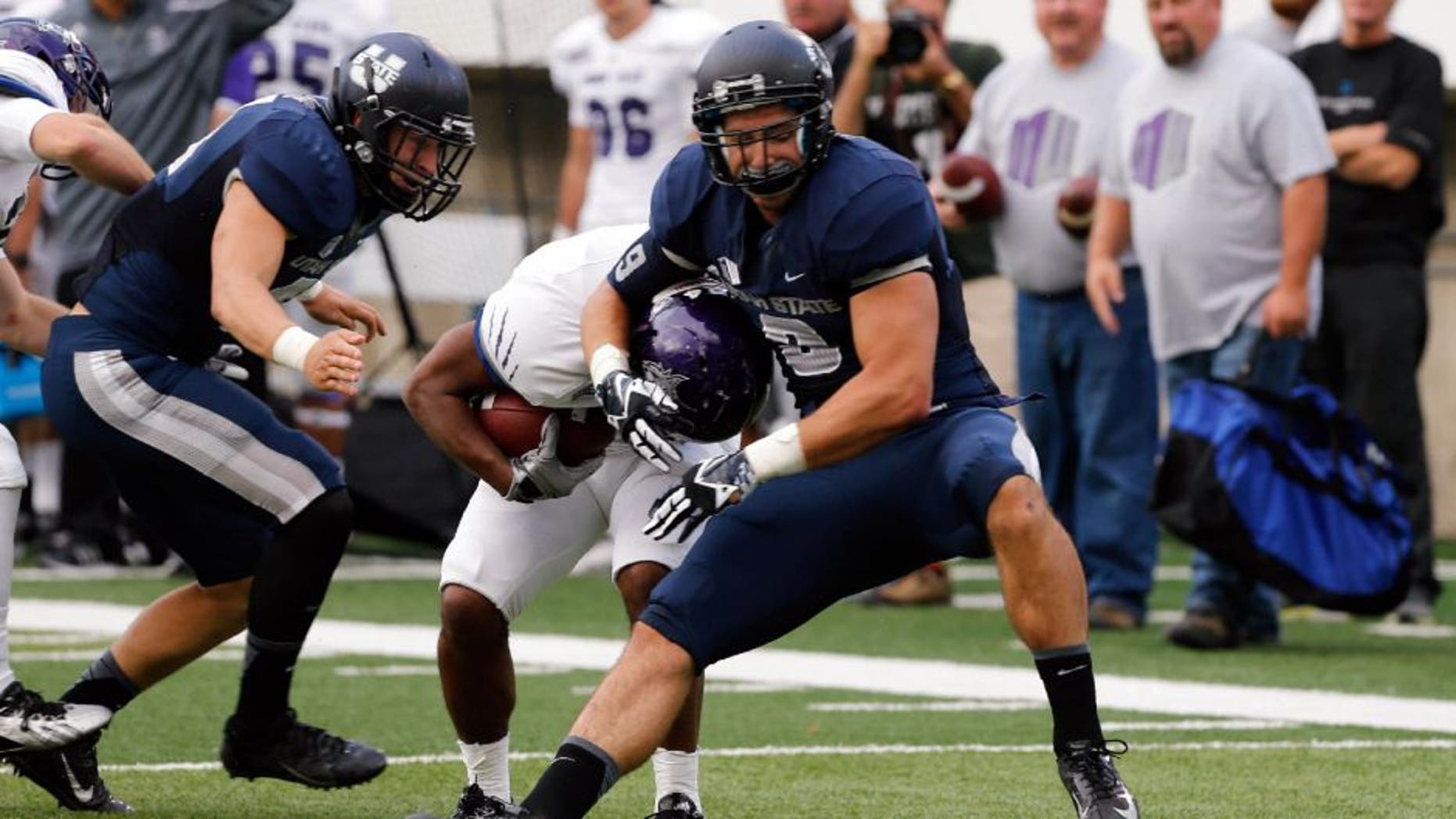 Sep 14, 2013; Logan, UT, USA; Utah State Aggies linebacker Kyler Fackrell (9) tackles Weber State Wildcats running back Josh Booker (24) during the second quarter at Romney Stadium. Mandatory Credit: Chris Nicoll-USA TODAY Sports