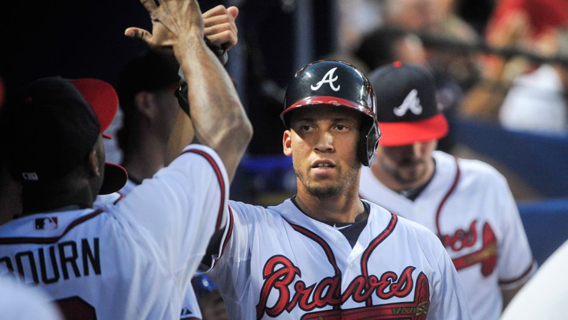 Atlanta Braves' Andrelton Simmons, right, is congratulated in the dugout after scoring on an RBI triple ground ball to right field by Atlanta Braves' Jace Peterson during the third inning of a baseball game, Friday, Aug. 14, 2015, in Atlanta. (AP Photo/John Amis)