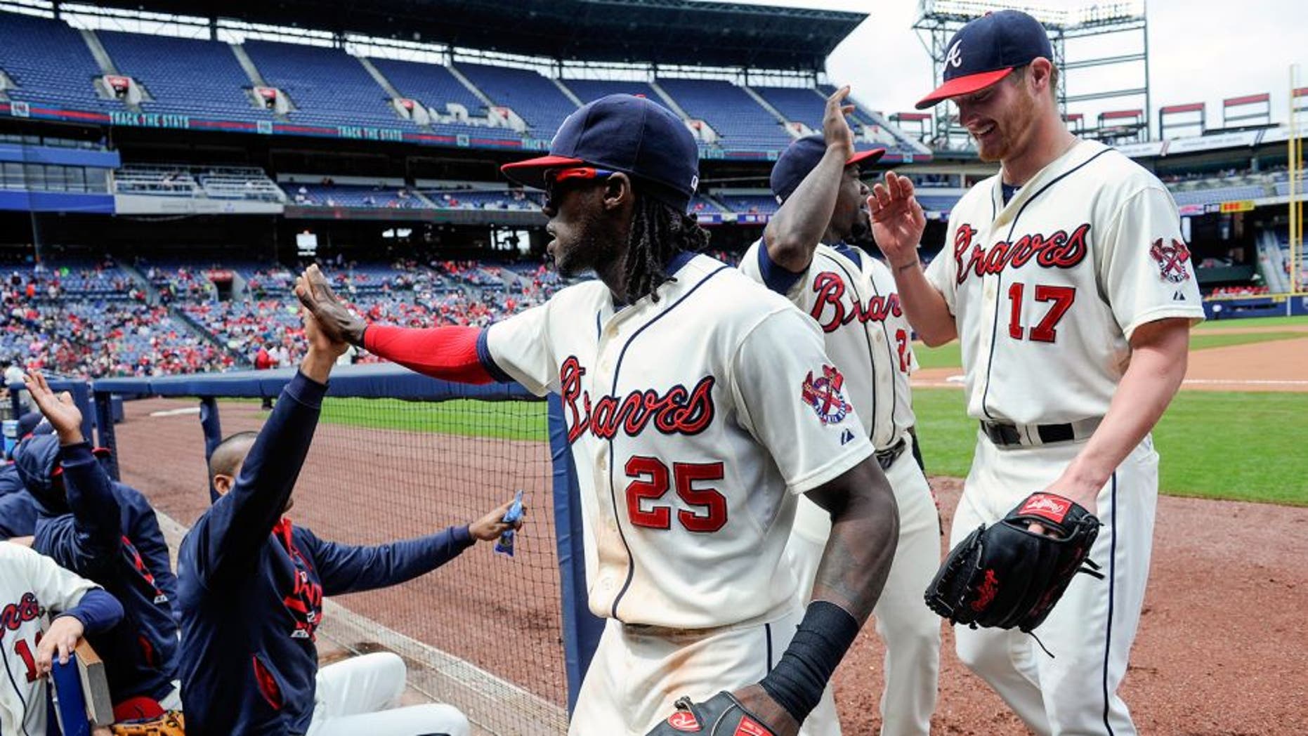 Atlanta Braves center fielder Cameron Maybin (25) is followed by pitcher Shelby Miller (17) as he is congratulated while entering the dugout after catching a fly ball hit by St. Louis Cardinals' Brandon Moss and throwing out Greg Garcia at first to turn a double play during the fourth inning of the first baseball game of a doubleheader, Sunday, Oct. 4, 2015, in Atlanta. (AP Photo/John Amis)