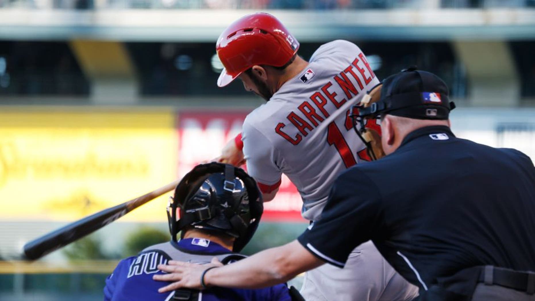 St. Louis Cardinals' Matt Carpenter, flies out as Colorado Rockies catcher Nick Hundley, center, and home plate umpire Mike Everitt look on in the first inning of a baseball game Monday, June 8, 2015, in Denver. (AP Photo/David Zalubowski)
