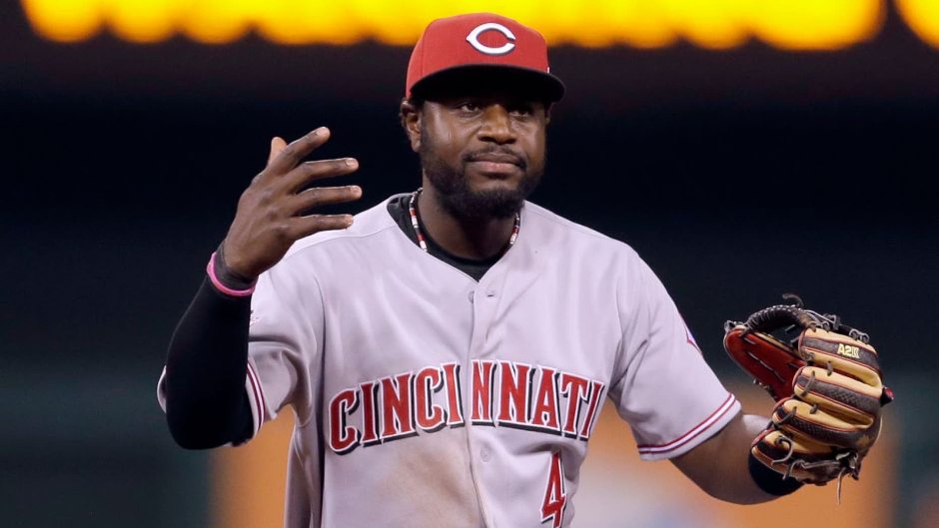 Cincinnati Reds second baseman Brandon Phillips throws up his hands after misplaying a ball hit by St. Louis Cardinals' Matt Adams during the eighth inning of a baseball game Friday, April 17, 2015, in St. Louis. The Cardinals' Matt Carpenter score and Phillips was charged with an error on the play. (AP Photo/Jeff Roberson)
