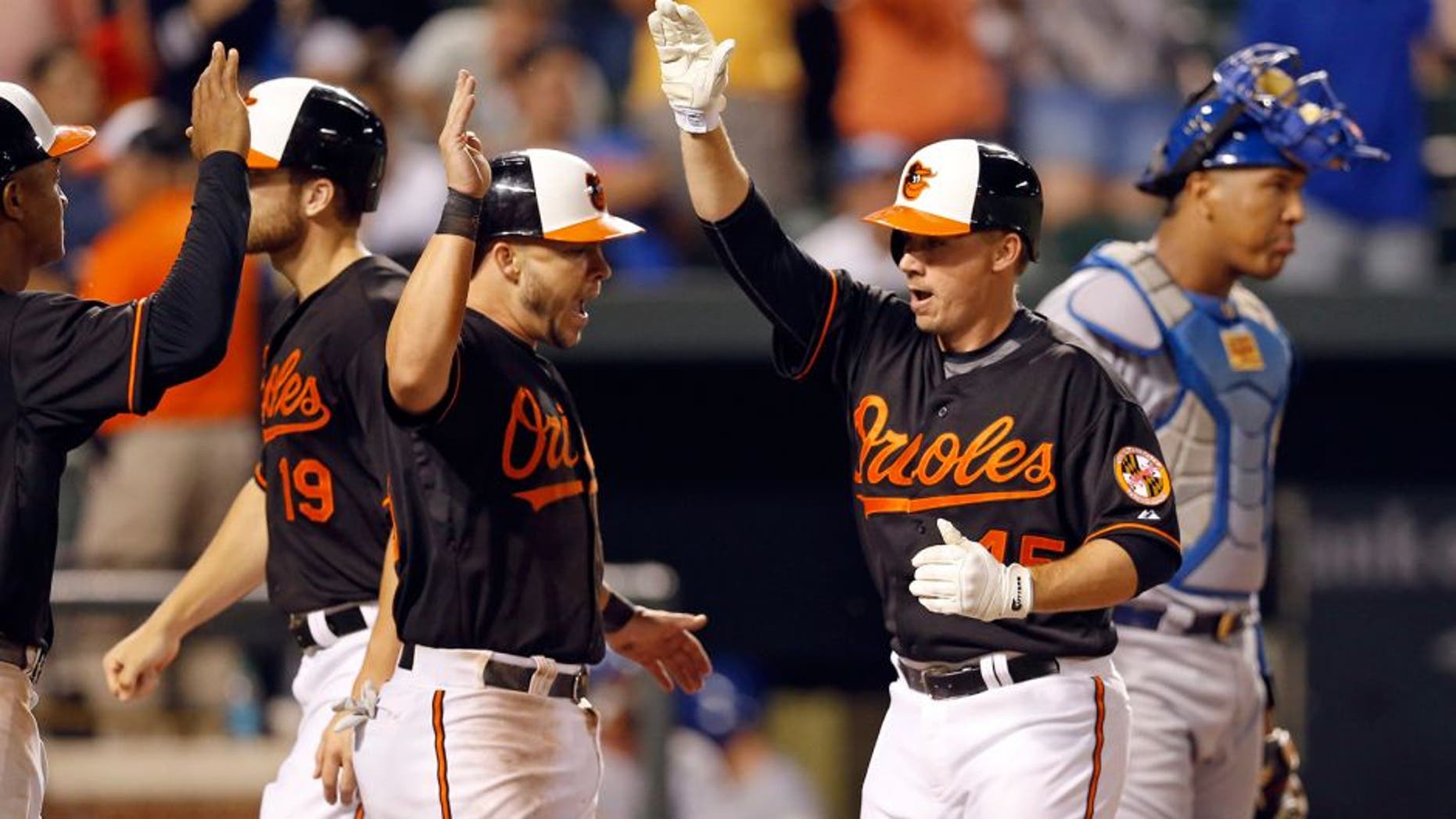 Baltimore Orioles' Steve Clevenger, second from right, celebrates his grand slam with teammates Jonathan Schoop, left, Chris Davis (19) and Steve Pearce, next to Kansas City Royals catcher Salvador Perez during the eighth inning of a baseball game, Friday, Sept. 11, 2015, in Baltimore. The Orioles won 14-8. (AP Photo/Patrick Semansky)