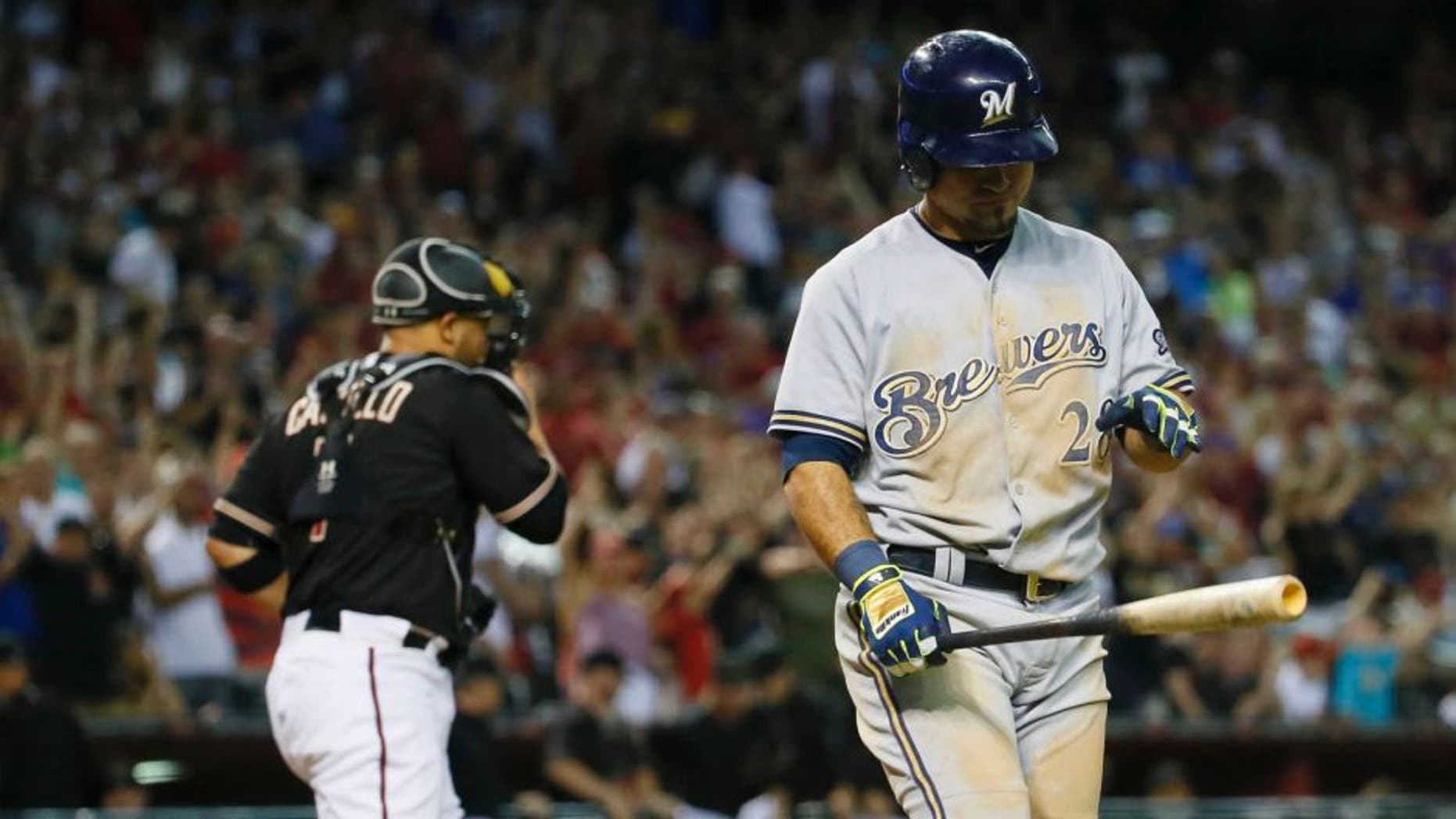The Milwaukee Brewers' Gerardo Parra walks to the dugout after striking out with the bases loaded to end the game as Arizona Diamondbacks catcher Welington Castillo runs to the mound, Saturday, July 25, 2015, in Phoenix. The Diamondbacks won 2-0.