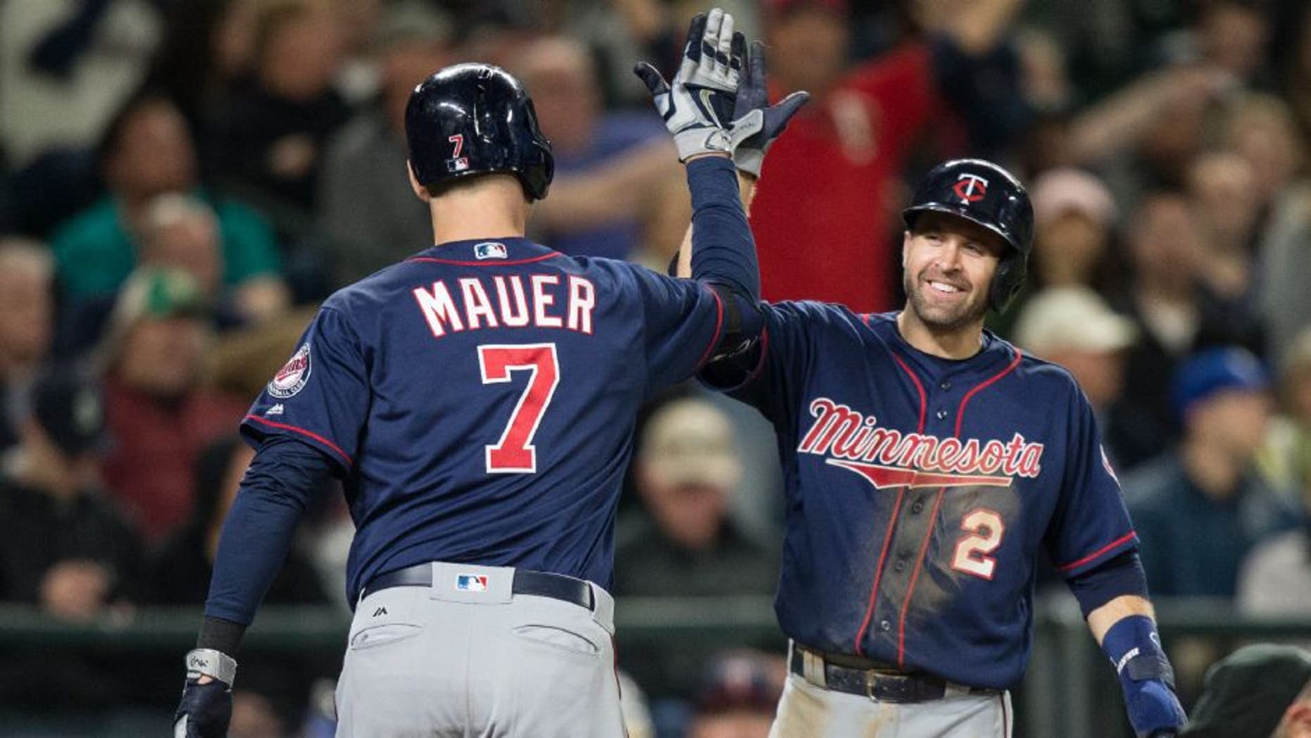 Minnesota Twins' Brian Dozier, right, congratulates Joe Mauer after Mauer hit a two-run home run that scored Dozier during the fifth inning of a baseball game against the Seattle Mariners.