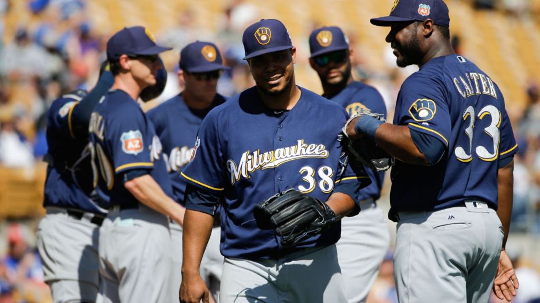 Milwaukee Brewers starting pitcher Wily Peralta, center, walks off the mound past Chris Carter, right, after he was relieved during the fourth inning of a spring training baseball game against the Los Angeles Dodgers Monday, March 14, 2016, in Phoenix.