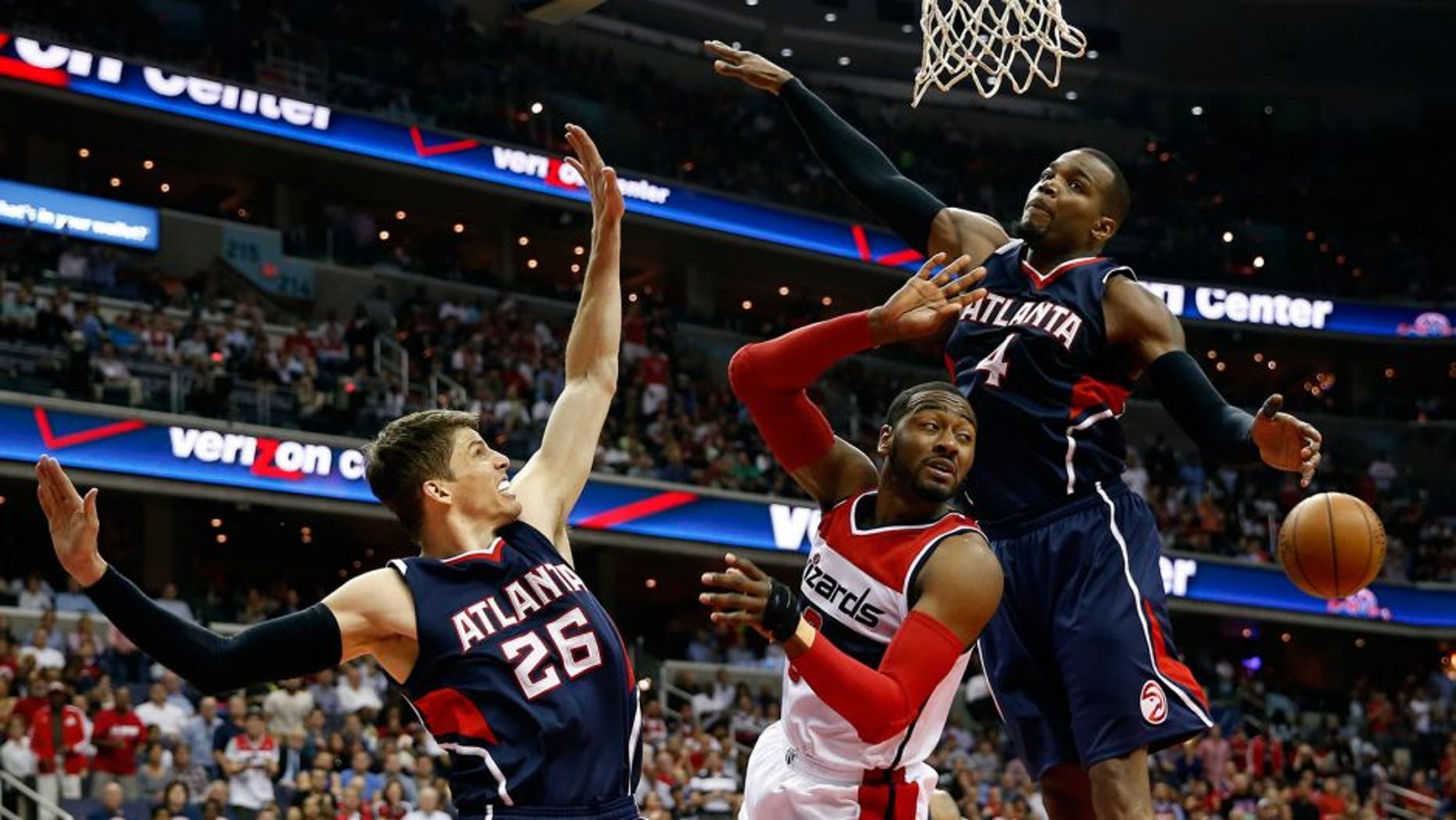 Washington Wizards guard John Wall, center, passes the ball between Atlanta Hawks guard Kyle Korver (26) and forward Paul Millsap (4) in the first half of Game 6 of the second round of the NBA basketball playoffs, Friday, May 15, 2015, in Washington. (AP Photo/Alex Brandon)