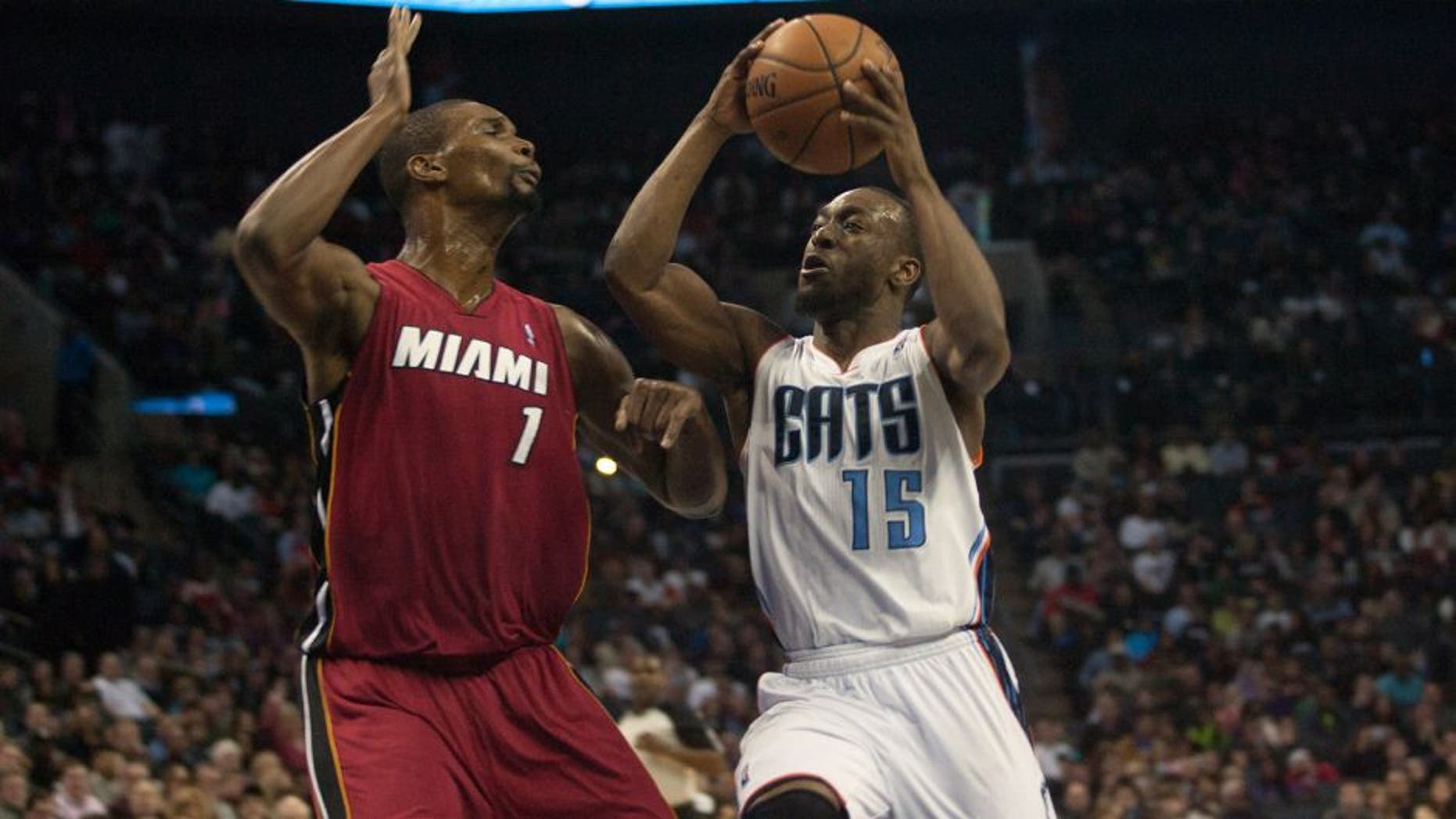 Jan 18, 2014; Charlotte, NC, USA; Charlotte Bobcats point guard Kemba Walker (15) goes up for a shot over Miami Heat center Chris Bosh (1) during the second half at Time Warner Cable Arena. The Heat defeated the Bobcats 104-96 in overtime. Mandatory Credit: Jeremy Brevard-USA TODAY Sports