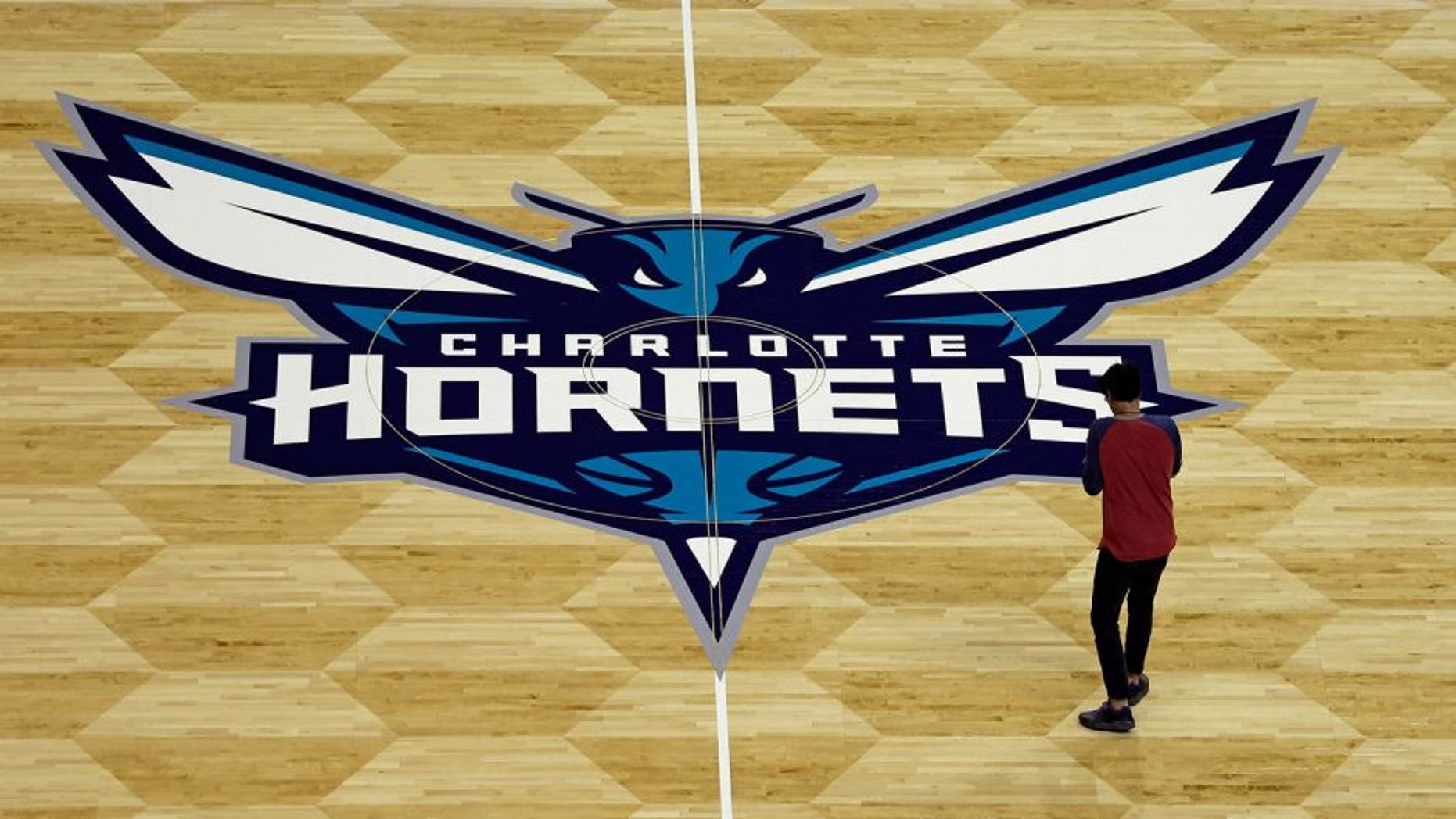 A photographer takes photos of the Charlotte Hornets logo during a news conference to unveil the design for their home court in Charlotte, N.C., Thursday, June 26, 2014. (AP Photo/Chuck Burton)