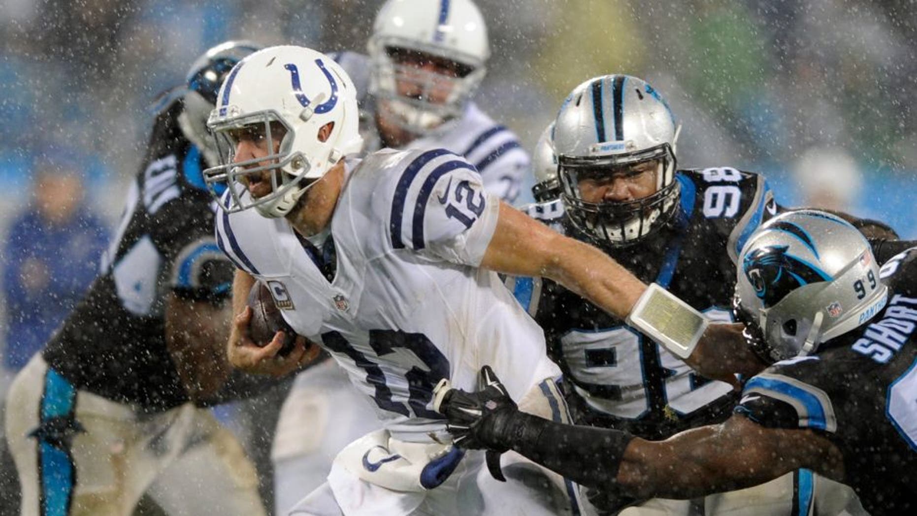 Indianapolis Colts' Andrew Luck (12) runs as Carolina Panthers' Kawann Short (99) defends in the first half of an NFL football game in Charlotte, N.C., Monday, Nov. 2, 2015. (AP Photo/Mike McCarn)