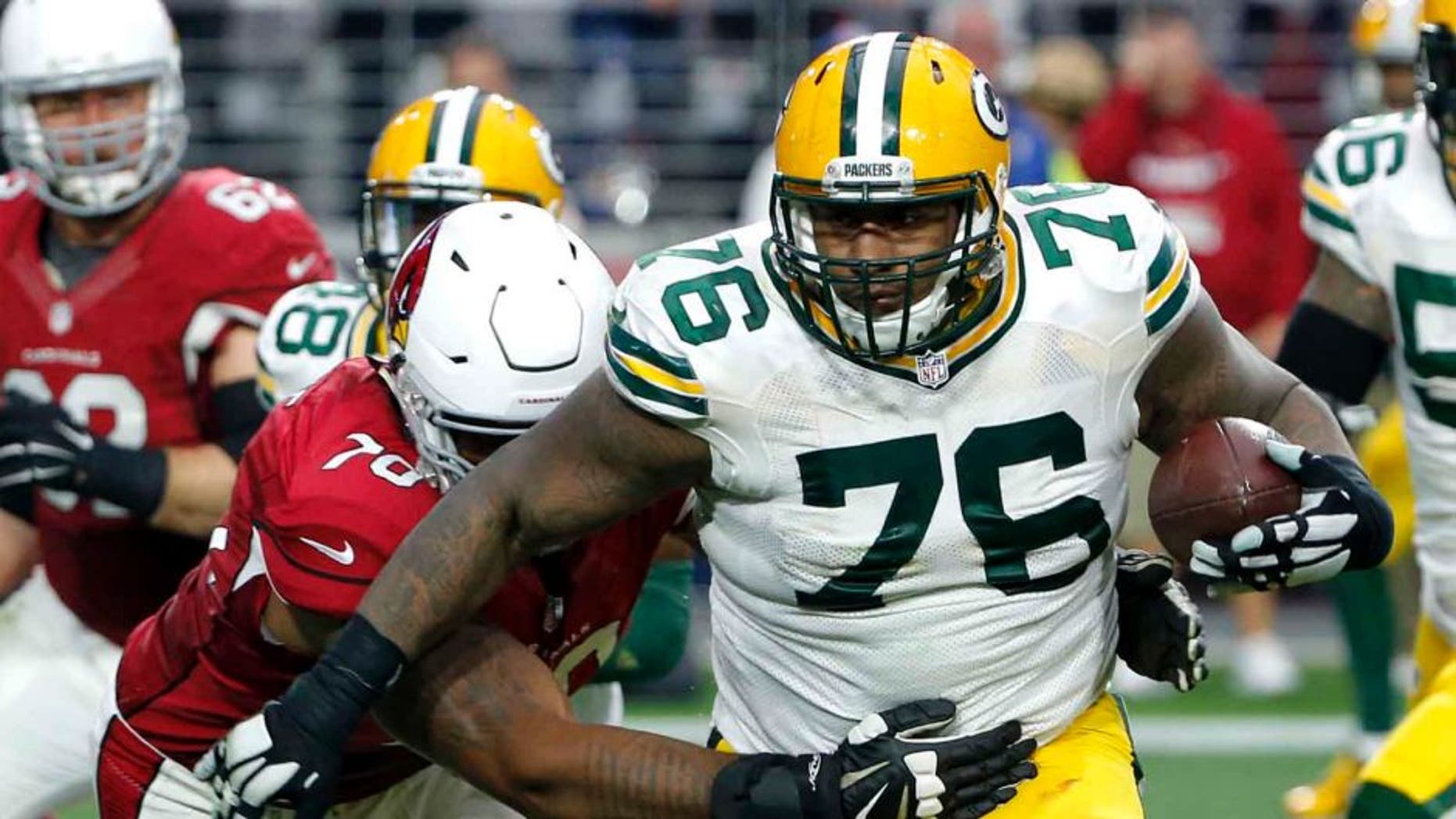 Green Bay Packers defensive end Mike Daniels runs back an interception as Arizona Cardinals tackle Bobby Massie defends during the first half Sunday, Dec. 27, 2015, in Glendale, Ariz.