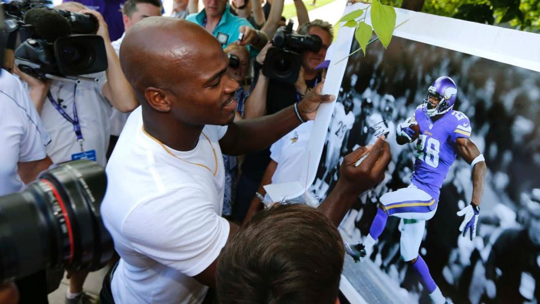 Minnesota Vikings running back Adrian Peterson signs autograph as he reports to an NFL football training camp at Minnesota State University Saturday, July 25, 2015, in Mankato, Minn.