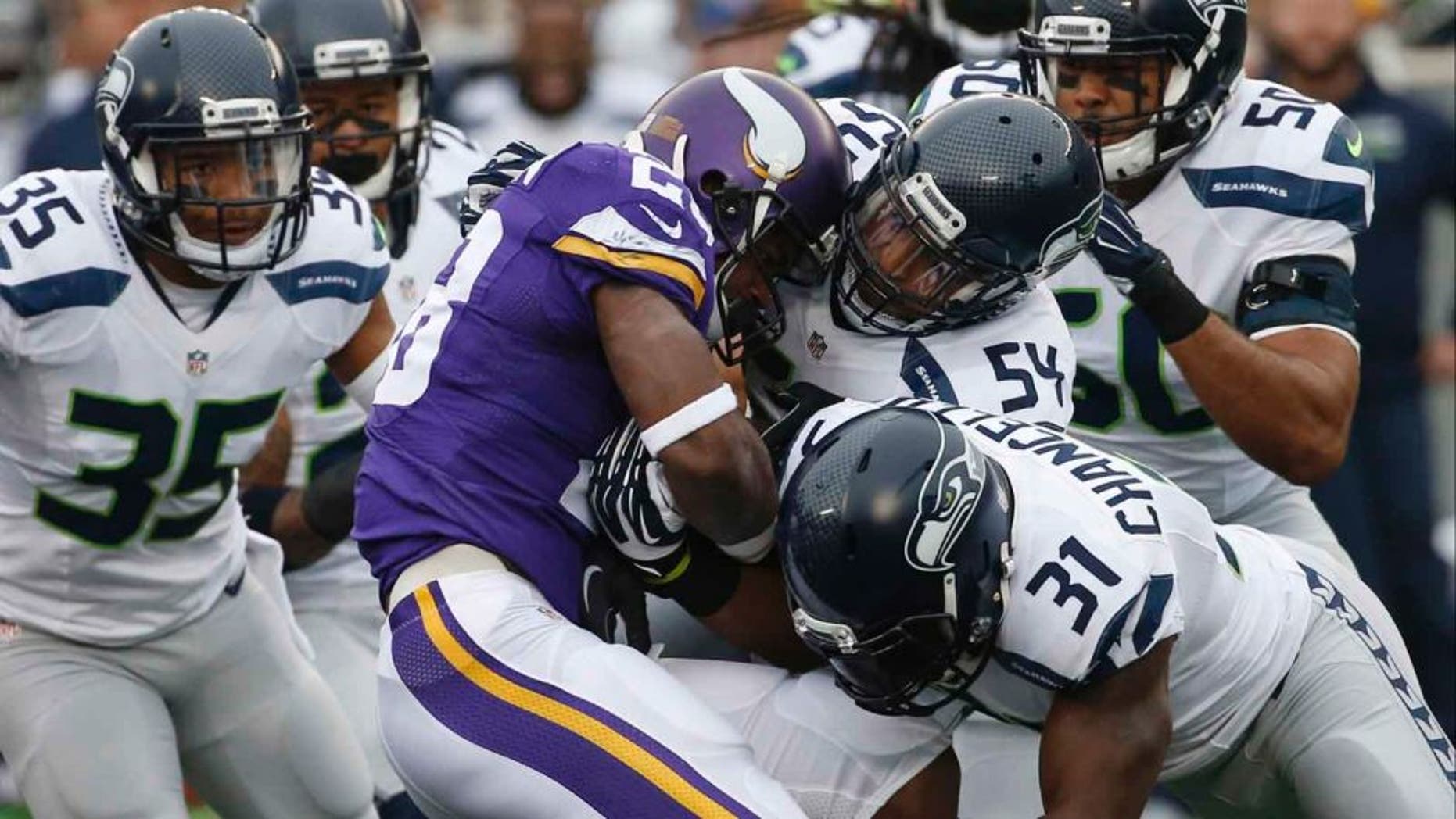 Minnesota Vikings running back Adrian Peterson is stopped by Seattle Seahawks defenders including linebacker Bobby Wagner (center) and strong safety Kam Chancellor (bottom right) in the first half of an NFL football game Sunday, Dec. 6, 2015 in Minneapolis.