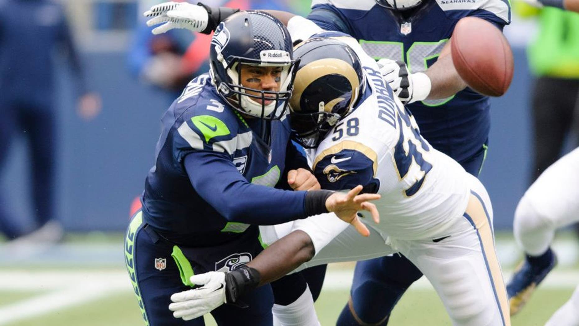 Dec 29, 2013; Seattle, WA, USA; Seattle Seahawks quarterback Russell Wilson (3) throws the ball as St. Louis Rams outside linebacker Jo-Lonn Dunbar (58) tackles during the first half at CenturyLink Field. Mandatory Credit: Steven Bisig-USA TODAY Sports