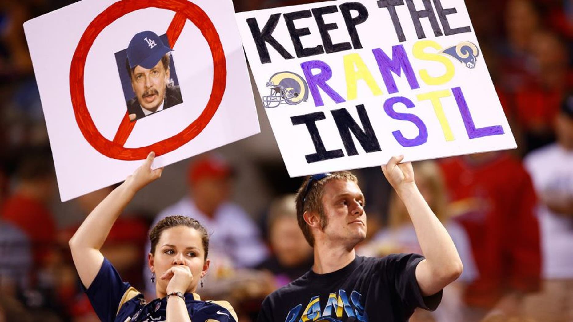 Fans hold up signs with a picture of St. Louis Rams owner Stan Kroenke and "Keep the Rams in STL" during a baseball game between the St. Louis Cardinals and Los Angeles Dodgers, Friday, May 29, 2015, in St. Louis. (AP Photo/Billy Hurst)