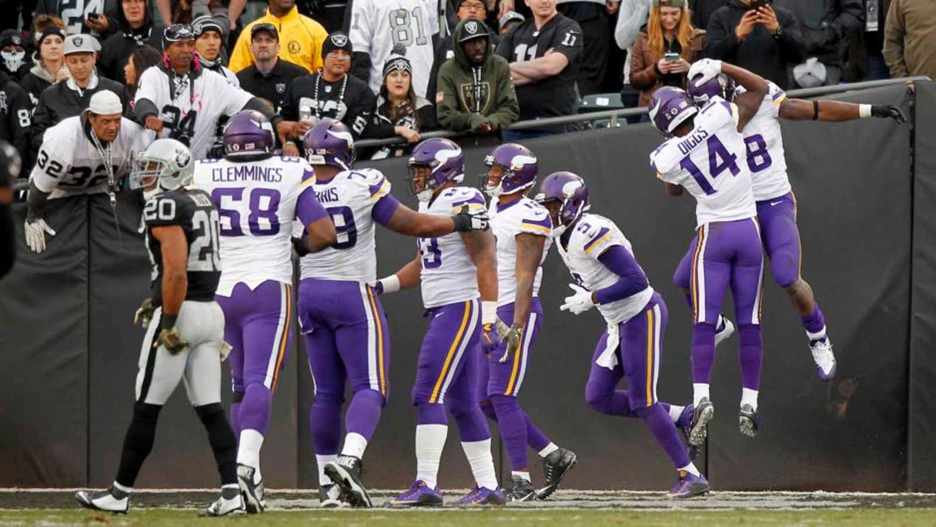 Minnesota Vikings running back Adrian Peterson (right) is congratulated by wide receiver Stefon Diggs (second from right) after rushing for a touchdown against the Oakland Raiders in the fourth quarter at O.co Coliseum in Oakland, Calif., on Sunday, Nov. 15, 2015. The Vikings won 30-14.