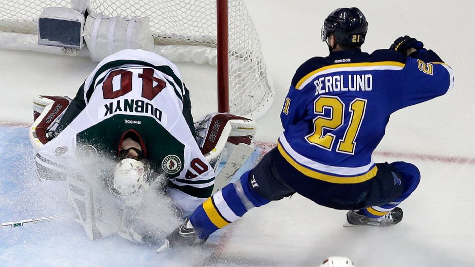Minnesota Wild goalie Devan Dubnyk, left, smothers a puck as he is sprayed by St. Louis Blues' Patrik Berglund, of Sweden, during the third period in Game 2 of an NHL hockey first-round playoff series, Saturday, April 18, 2015, in St. Louis. The Blues won 4-1 to tie the series 1-1. (AP Photo/Jeff Roberson)