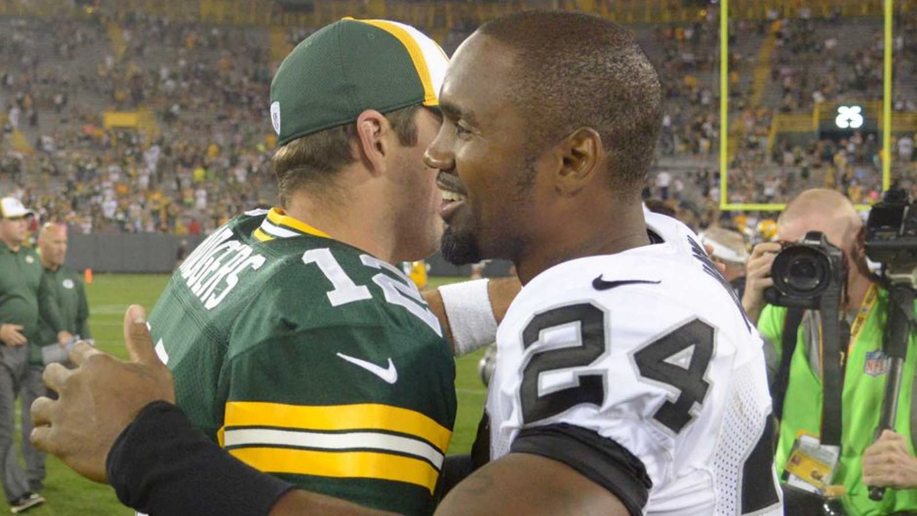 Aug 22, 2014; Green Bay, WI, USA; Green Bay Packers quarterback Aaron Rodgers (12) and Oakland Raiders safety Charles Woodson (24) embrace after the game at Lambeau Field. The Packers defeated the Raiders 31-21. Mandatory Credit: Kirby Lee-USA TODAY Sports