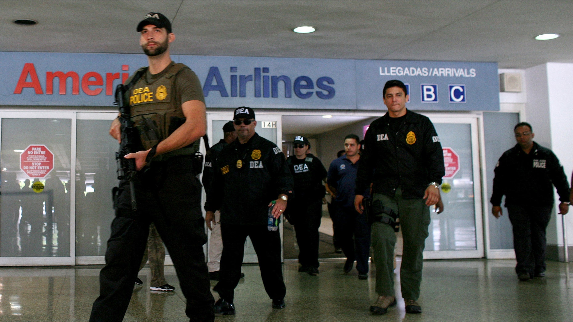 FILE - In this June 6, 2012 file photo, federal agents with the Drug Enforcement Administration escort a handcuffed drug smuggling suspect, at the airport in San Juan, Puerto Rico. U.S. federal agents will start targeting high-level drug traffickers in Puerto Rico after gathering intelligence during a three-month blitz on criminal activity in the U.S. territory, the Department of Homeland Security said Thursday, Sept. 26, 2013 (AP Photo/Ricardo Arduengo)
