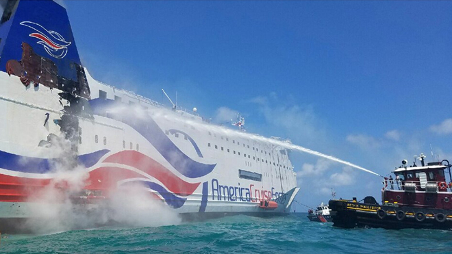 In this photo provided by the U.S. Coast Guard, a local San Juan, Puerto Rico-based tug crew uses a fire hose to cool the hull of the Caribbean Fantasy cruise ship that caught fire, a mile from San Juan Harbor, Puerto Rico, Wednesday, Aug. 17, 2016. More than 500 passengers and crew were evacuated from a burning ship off Puerto Rico's north coast and many required medical care, though there were no reported fatalities or life-threatening injuries. (Petty Officer 2nd Class Jonathan Lally/US Coast Guard via AP)