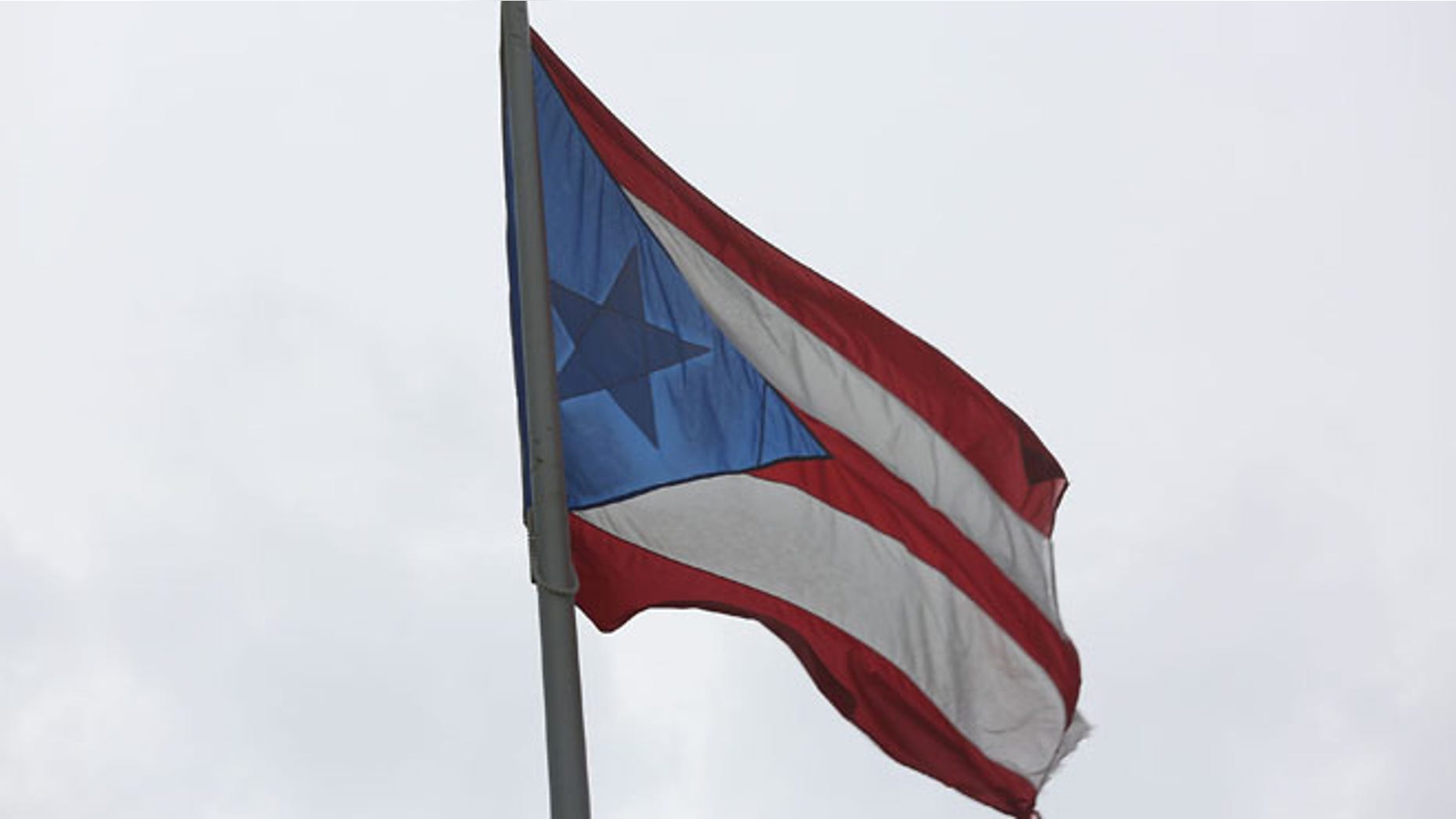 SAN JUAN, PUERTO RICO - JULY 01: The Puerto Rican flag flies near the Capitol building as the island's residents deal with the government's $72 billion debt on July 1, 2015 in San Juan, Puerto Rico. Governor of Puerto Rico Alejandro GarcÃa Padilla said in a speech recently that the people of Puerto Rico will have to make sacrifices and share the responsibilities to help pull the island out of debt. (Photo by Joe Raedle/Getty Images)