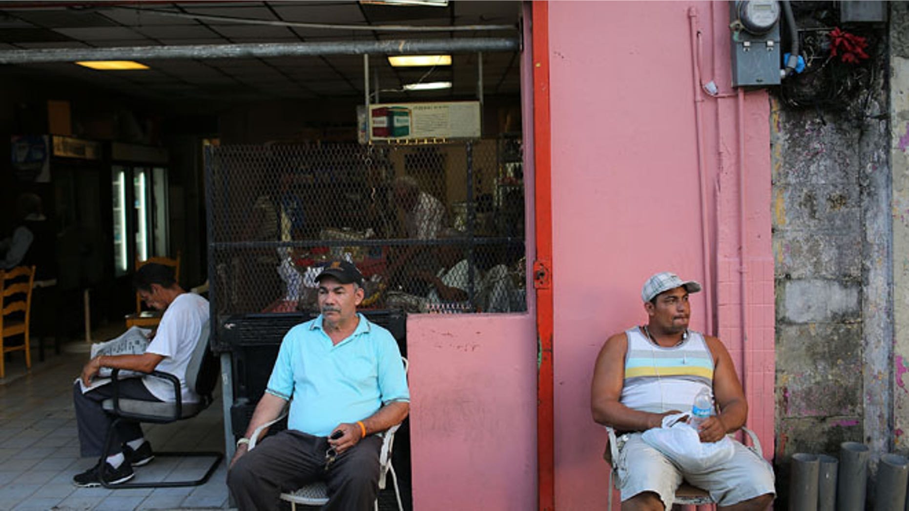 SAN JUAN, PUERTO RICO - JUNE 30: Valerio Ginairs (L) and Ricardo de la Cruz relax outside a bar a day after Puerto Rican Governor Alejandro Garcia Padilla gave a televised speech regarding the governments $72 billion debt on June 30, 2015 in San Juan, Puerto Rico. The governor said in his speech that the people will have to sacrifice and share in the responsibilities for pulling the island out of debt. (Photo by Joe Raedle/Getty Images)