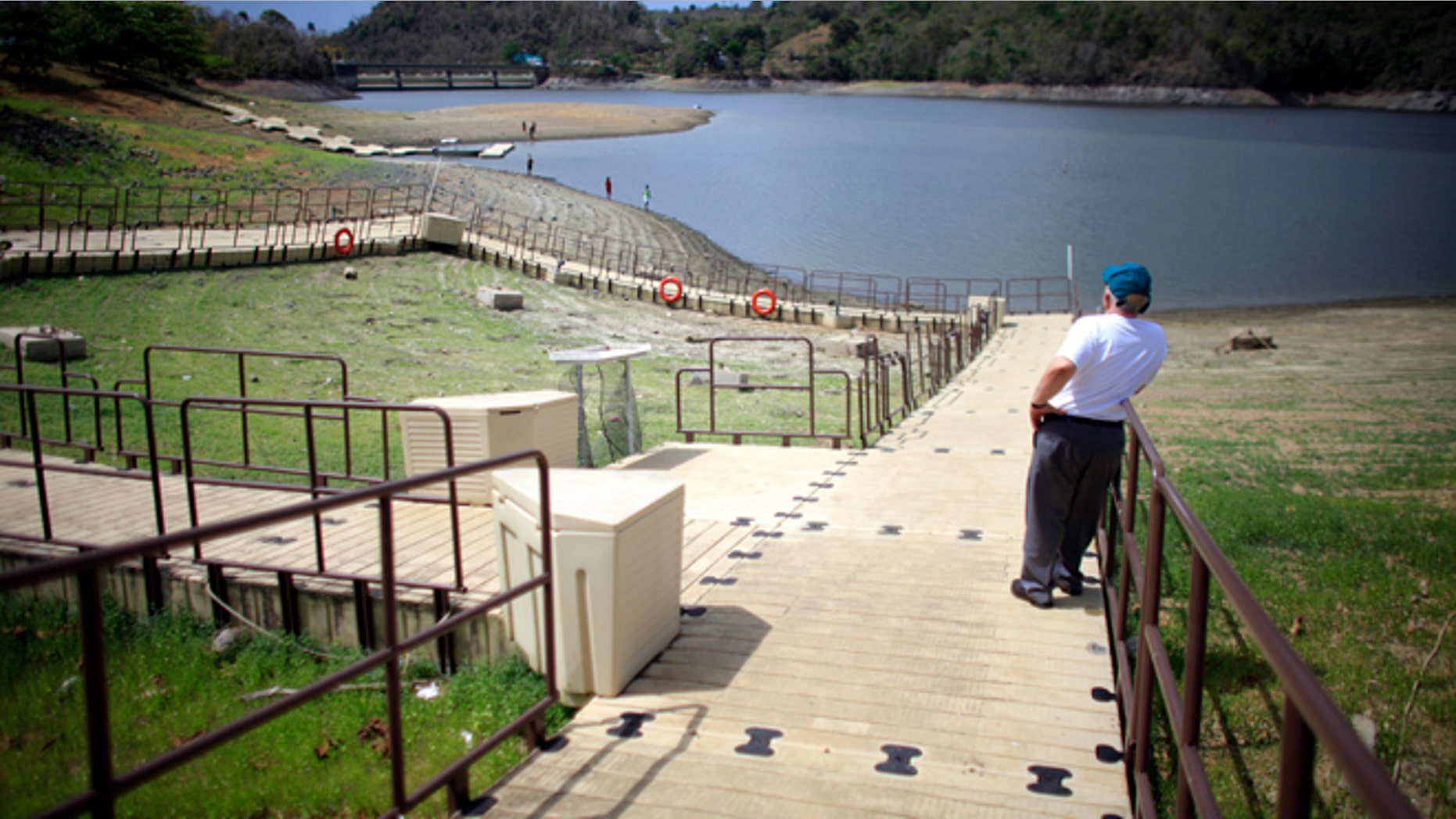 A man stands on a floating dock, laying on the unusually dry banks of the La Plata reservoir in Toa Alta, Puerto Rico, Wednesday, May 13, 2015. Puerto Rico imposed strict water-rationing measures Wednesday and Gov. Alejandro Garcia Padilla recently declared a state of emergency given the increasingly dry conditions. (AP Photo/Ricardo Arduengo)