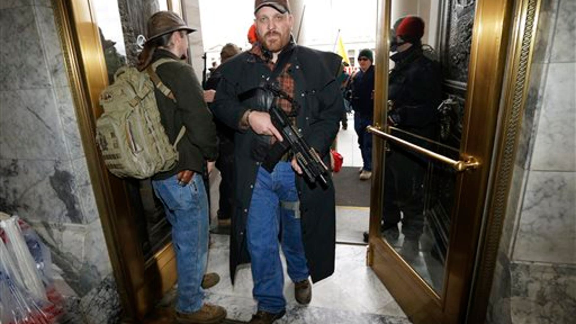 Jason McMillon carries his Rock River LAR-PDS pistol with a 45-round magazine into the Legislative Building at the Capitol in Olympia, Wash., Thursday, Jan. 15, 2015, during a gun-rights rally opposing the state's Initiative 594, which requires - with only a few exceptions - background checks on all gun sales and transfers. Rules at the Capitol allow guns to be carried openly in the building. (AP Photo/Ted S. Warren)