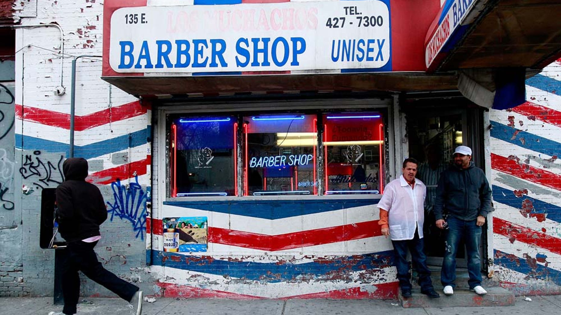 NEW YORK - JANUARY 06: Men stand outside a barber shop as the Three Kings Day Parade passes in East Harlem January 6, 2009 in New York City. The parade celebrates the Feast of the Epiphany, also known as Three Kings Day, marking the Biblical story of the visit of three kings to Bethlehem to visit the baby Jesus, revealing his divinity. (Photo by Mario Tama/Getty Images)
