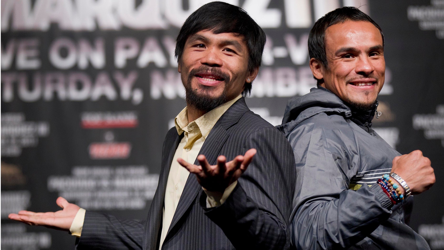 Manny Pacquiao, left, jokes with members of the media while posing for photos with Juan Manuel Marquez during a news conference Wednesday, Nov. 9, 2011, in Las Vegas. Pacquiao and Marquez are scheduled to meet for boxing's WBO welterweight title on Saturday. (AP Photo/Julie Jacobson)