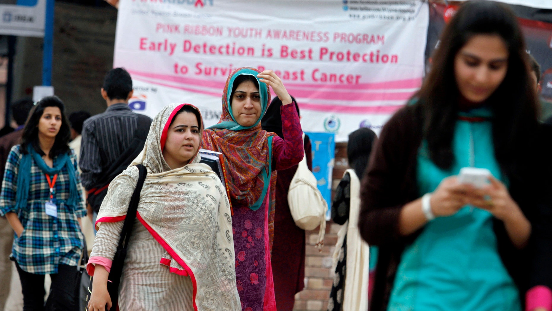 Students walk past a banner promoting awareness on breast cancer at a university in Islamabad, Pakistan. (AP Photo/Anjum Naveed)