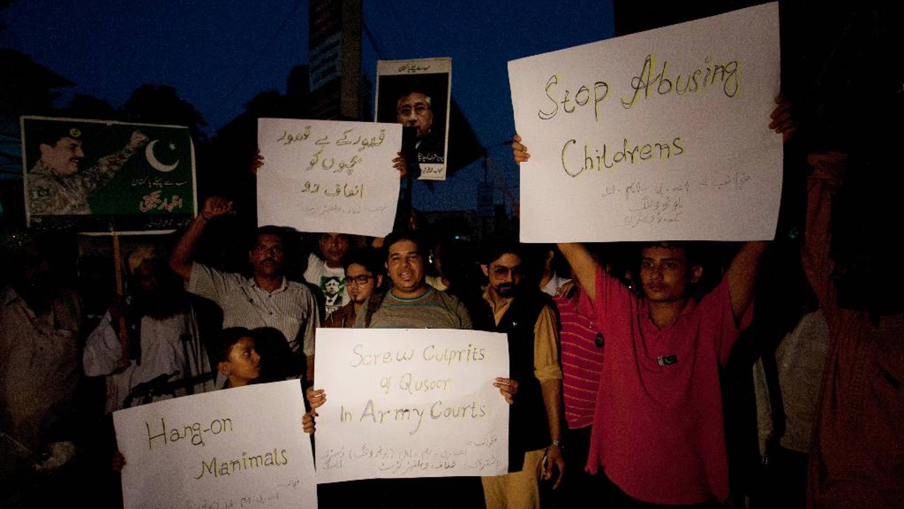 Activists from Pakistan's civil society hold placards to condemn a child abuse scandal, while holding a rally in Karachi, Pakistan, Tuesday, Aug. 11, 2015. In the Pakistani town of Hussain Khan Wala, near the border with India, families kept quiet for years about the blackmail gang that locals believe filmed some 270 children being sexually abused, fearful the videos could appear online or sold in markets for as little as 50 cents. The placard at upper left reads in Urdu, "Give justice to innocent children." (AP Photo/Shakil Adil)