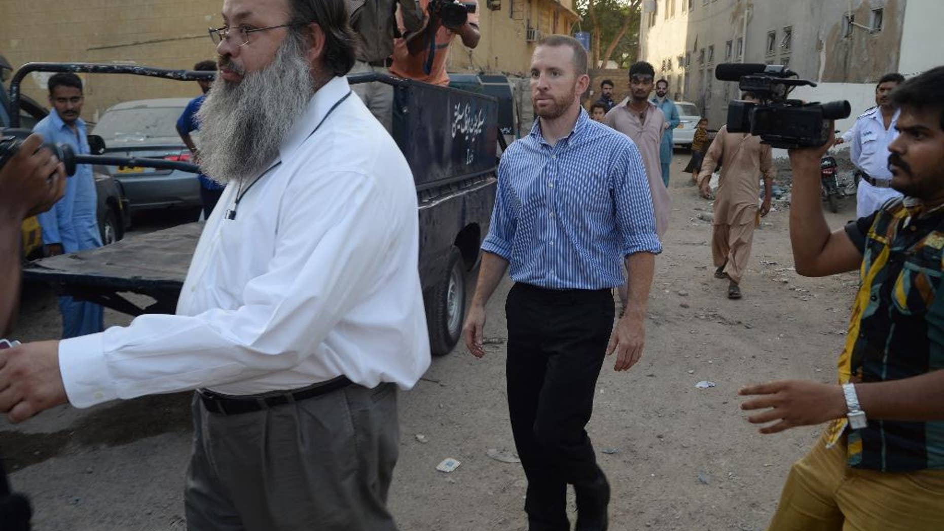 An American national, center, reportedly working for the FBI, leaves a police station in Karachi, Pakistan, Thursday, May 8, 2014. Pakistan released an FBI agent on bail Thursday after three days in custody, officials said, a move that is likely to prevent the situation from escalating into a diplomatic spat. The American man was detained after airport authorities found him carrying ammunition and three knives Monday as he was about to board a flight for the Pakistani capital, Islamabad.(AP Photo/Mohammad Khalil)