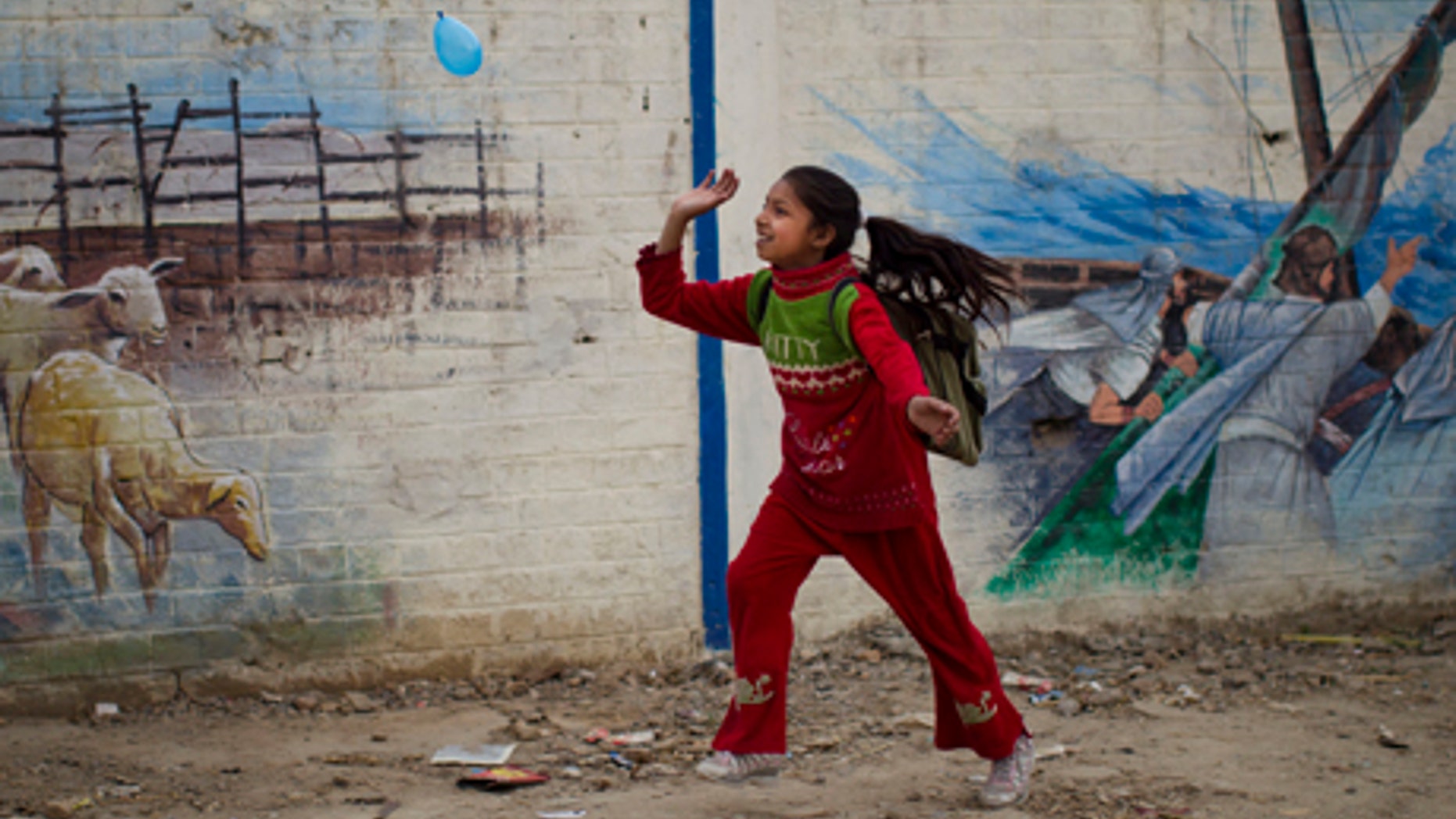 March 11, 2012: A Pakistani Christian girl plays with a balloon next to a wall with biblical paintings at the Christian colony in the center of Islamabad, Pakistan. Roughly five percent of Pakistan's 180 million people belong to minority religions, which include Hindu, Christian, Shiite Muslims and Ahmedis, according to the CIA World Factbook.