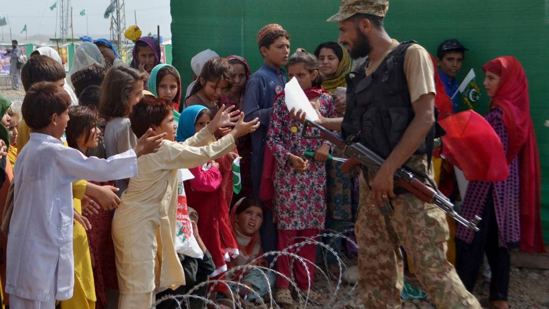 A soldier of the Pakistan army distributes a piece of ice among children displaced from Pakistani tribal area of North Waziristan, where Pakistan army is fighting against Taliban and militants, on the occasion Independence Day on Thursday, Aug. 14, 2014, in Bannu, Pakistan. Pakistanis commemorated its independence from British colonial rule in 1947. (AP Photo/Mohammad Sajjad)
