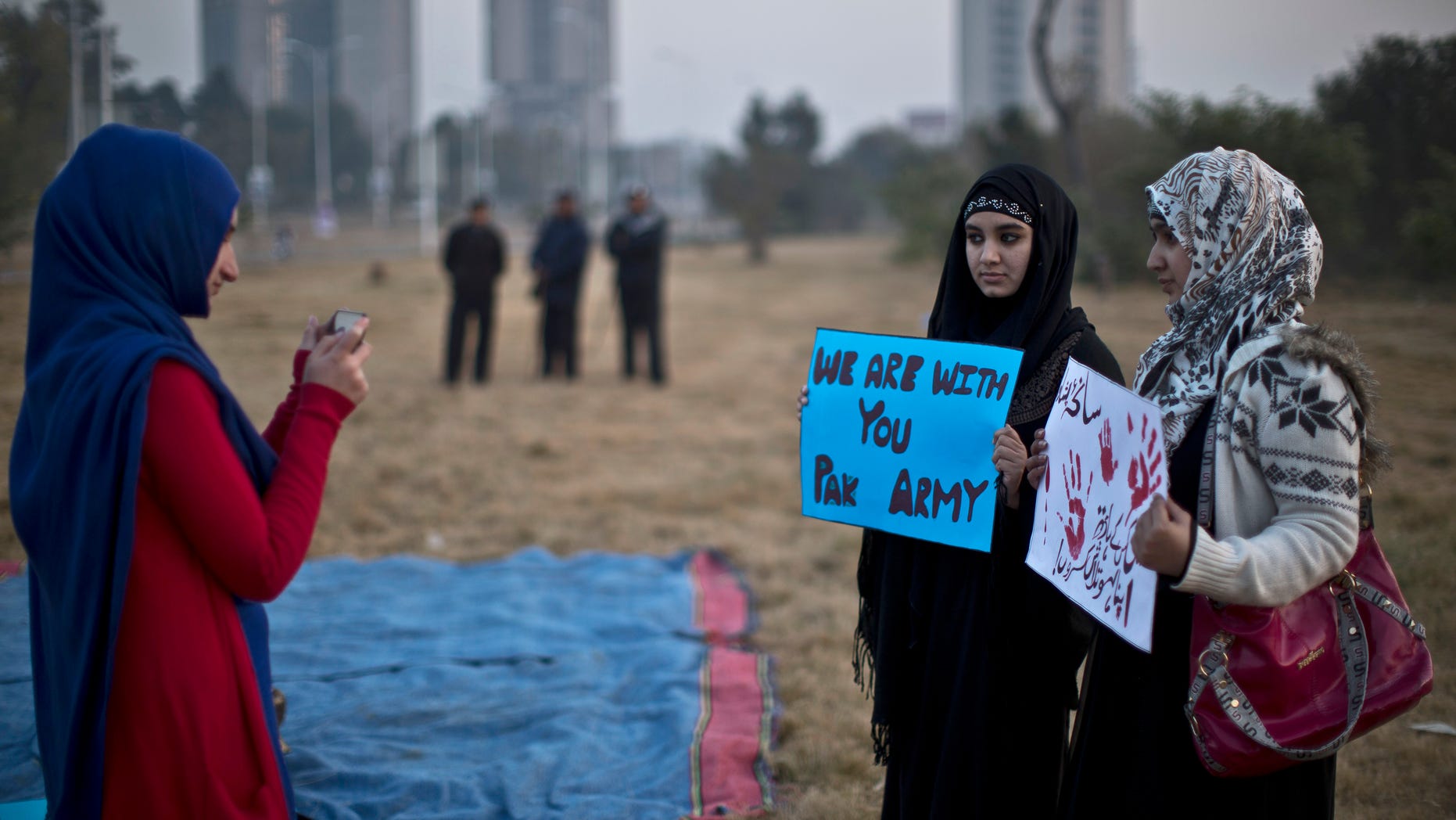 Dec. 19, 2014 - A Pakistani university student takes a picture of her friends holding banners prior to a protest condemning Tuesday's Taliban attack on a military-run school in Peshawar, in Islamabad, Pakistan that left 148 dead. Pakistani warplanes and ground forces killed at least 77 militants in a northwestern tribal region near the Afghan border.