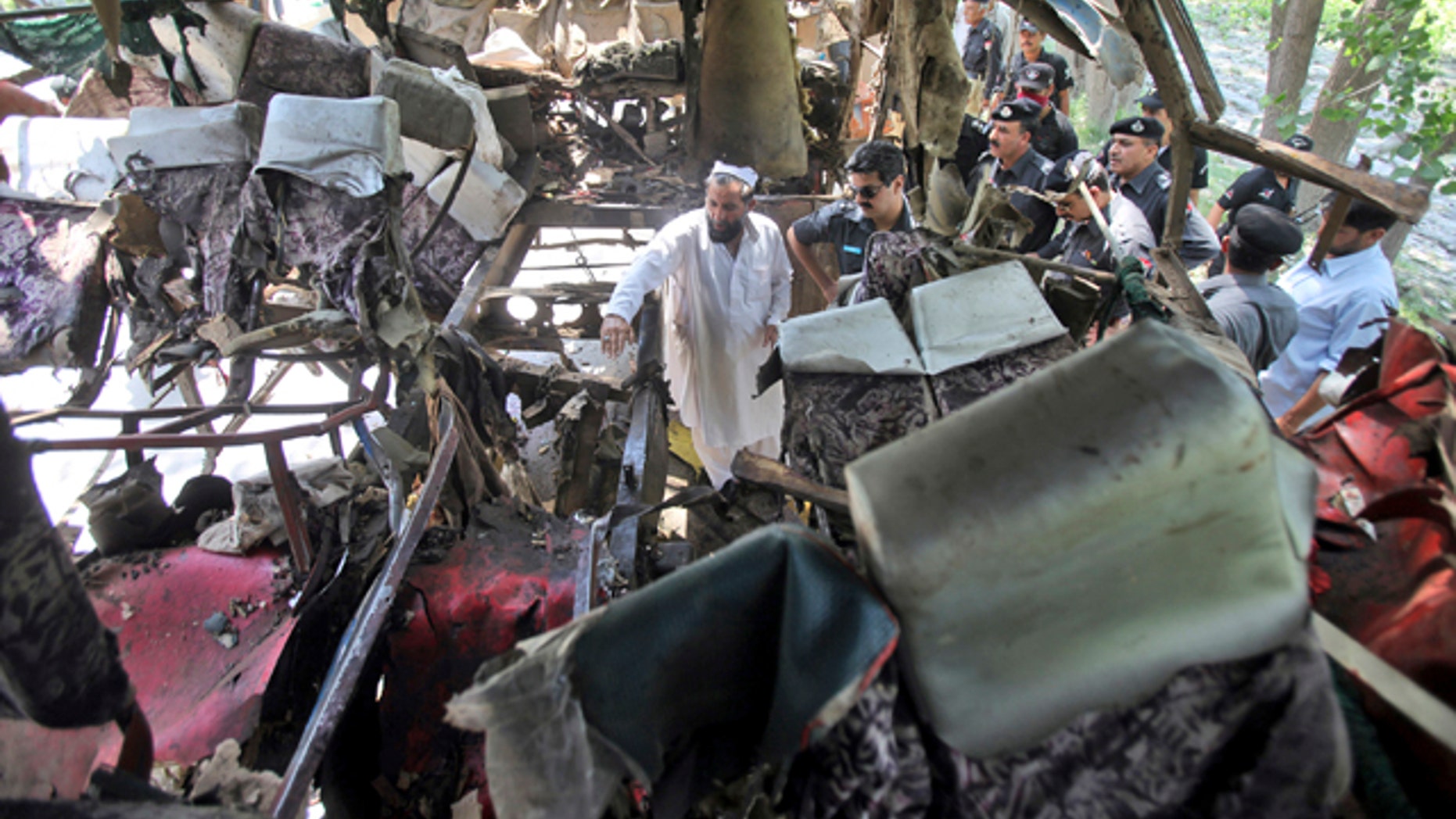 June 8, 2012: Pakistani police officers check the wreckage of a bus that exploded when a bomb planted in it went off on the outskirts of Peshawar, Pakistan.