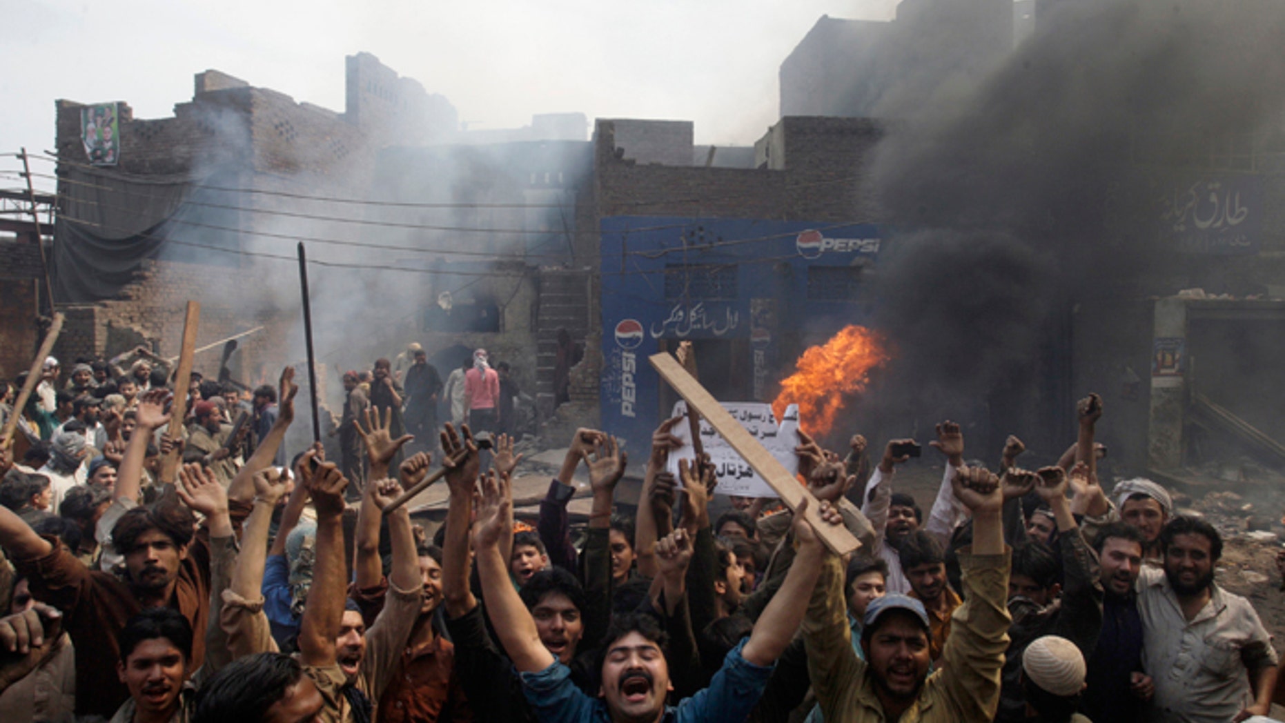An angry mob reacts after burning Christian houses in Lahore, Pakistan, on Saturday. (AP Photo/K.M. Chaudary)
