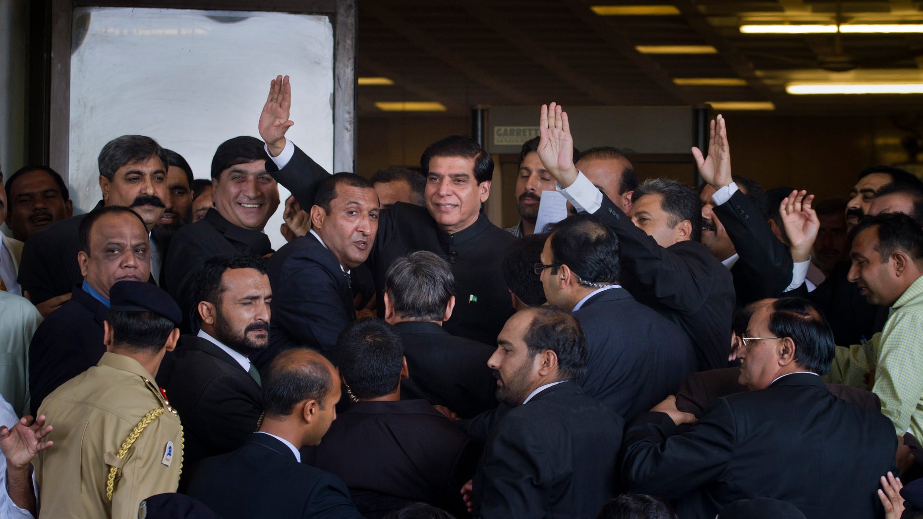 Aug. 27, 2012: Pakistan's Prime Minister Raja Pervaiz Ashraf, center, waves as he is surrounded by security staff upon his arrival at the Supreme Court for a hearing in Islamabad, Pakistan.