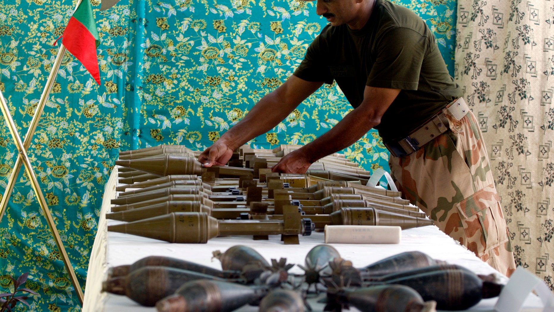 A Pakistani army soldier arranges weapons reportedly recovered from hideouts of militants in tribal areas, as they are displayed in Peshawar, Pakistan on Wednesday, Aug. 29, 2012. (AP Photo/Mohammad Sajjad)