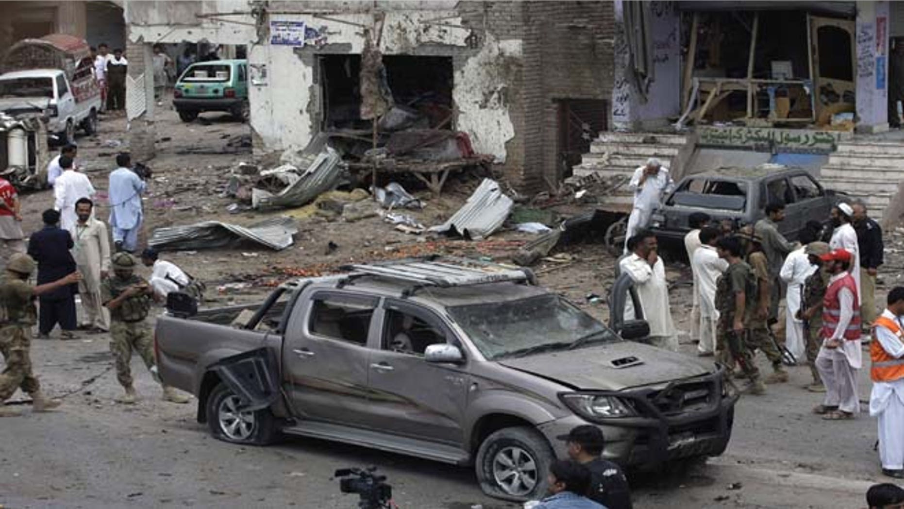 June 30, 2013: Pakistani security officials and rescue workers examine the site of car bombing on the outskirts of Peshawar, Pakistan. A car bomb exploded as a convoy of paramilitary troops passed through the outskirts of the northwest Pakistani city of Peshawar, killing more than a dozen people and wounding scores of others, police said.