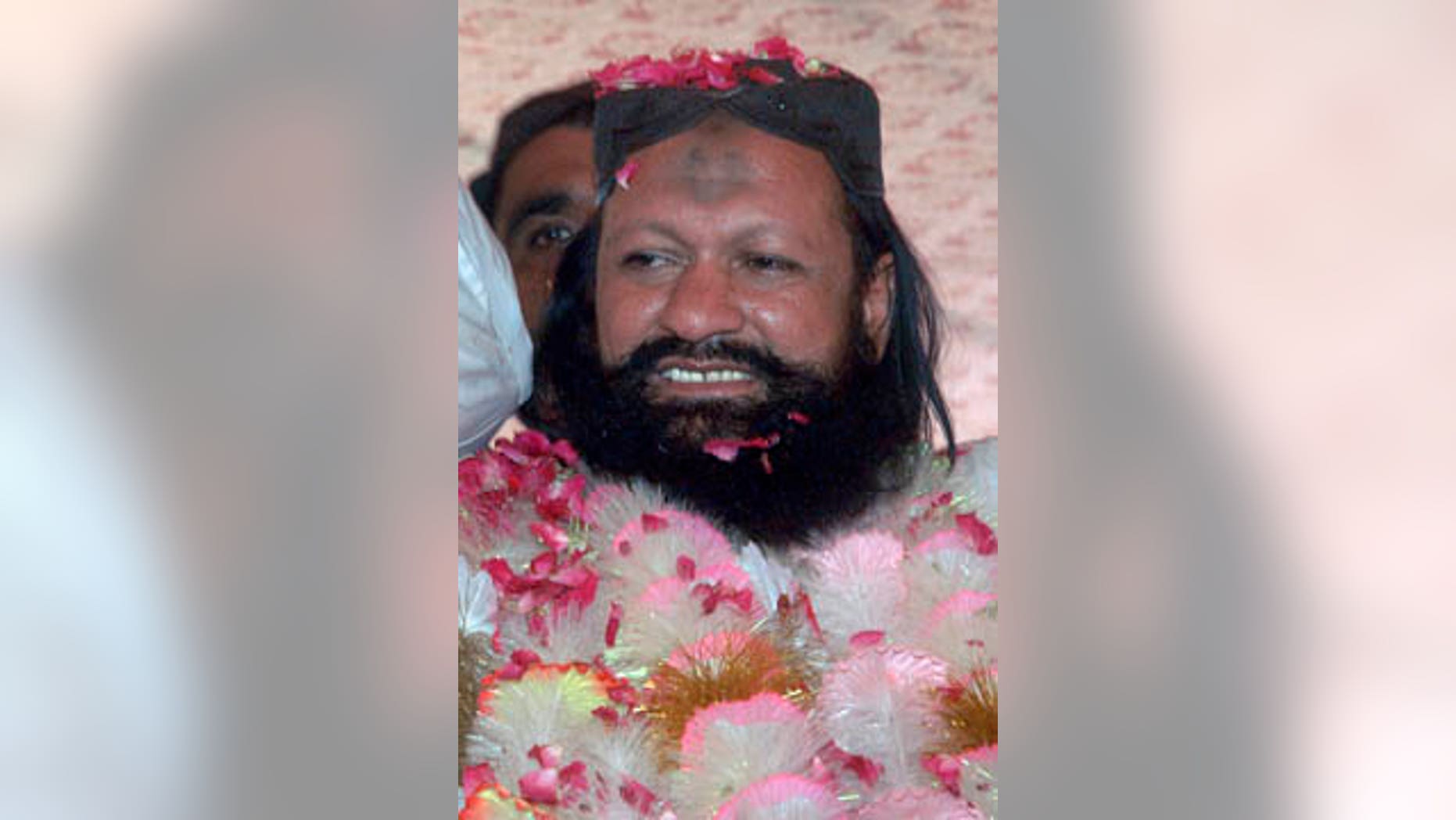 FILE - In this July 15, 2011, file photo, Malik Ishaq, a leader of the banned Sunni Muslim group Lashkar-e-Jhangvi, is greeted by supporters with rose-petals upon his arrival at his hometown in Rahim Yar Khan, Pakistan, after his release from jail. (AP Photo/Khalid Tanveer, File)