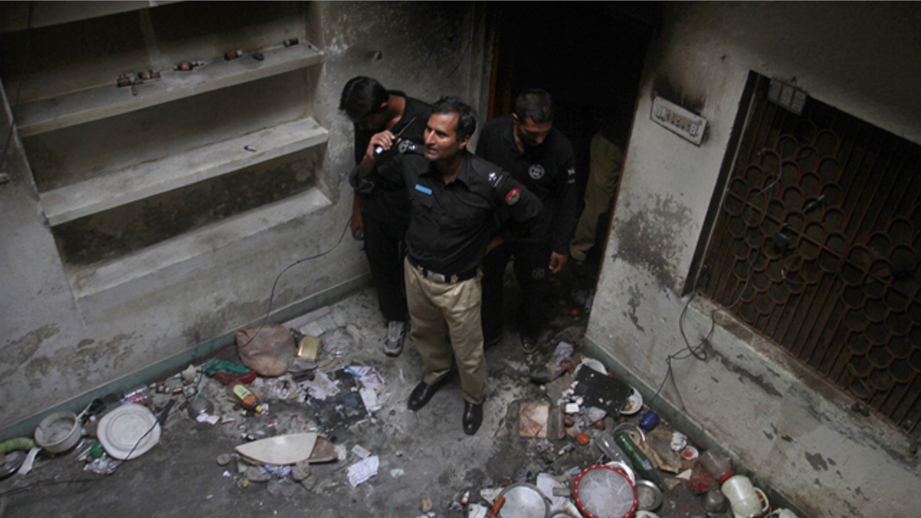 July 28, 2014: Pakistani police officers examine a house of a family belonging to the Ahmadi sect, which was torched by angry mob in Gujranwala, Pakistan. (AP Photo/K.M. Chaudary)