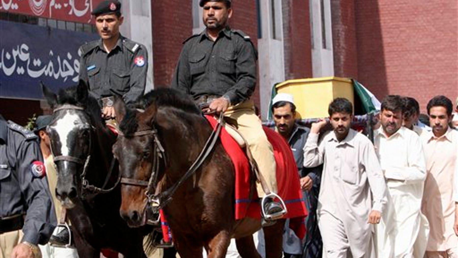 May 18: Pakistani police officers ride horses in front of relatives of one of two officers, who were killed in an attack by militants at a security checkpoint, carrying his body during his funeral procession in Peshawar, Pakistan.