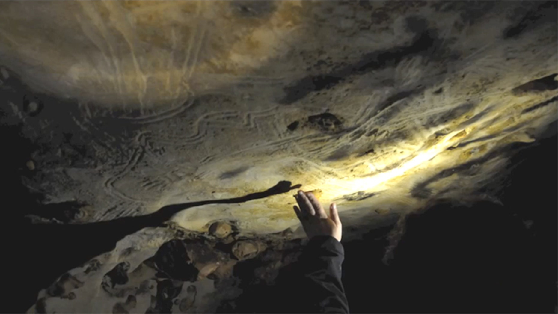 A researcher demonstrates how ancient people "hand fluted" the walls of a cave in France in this video still.