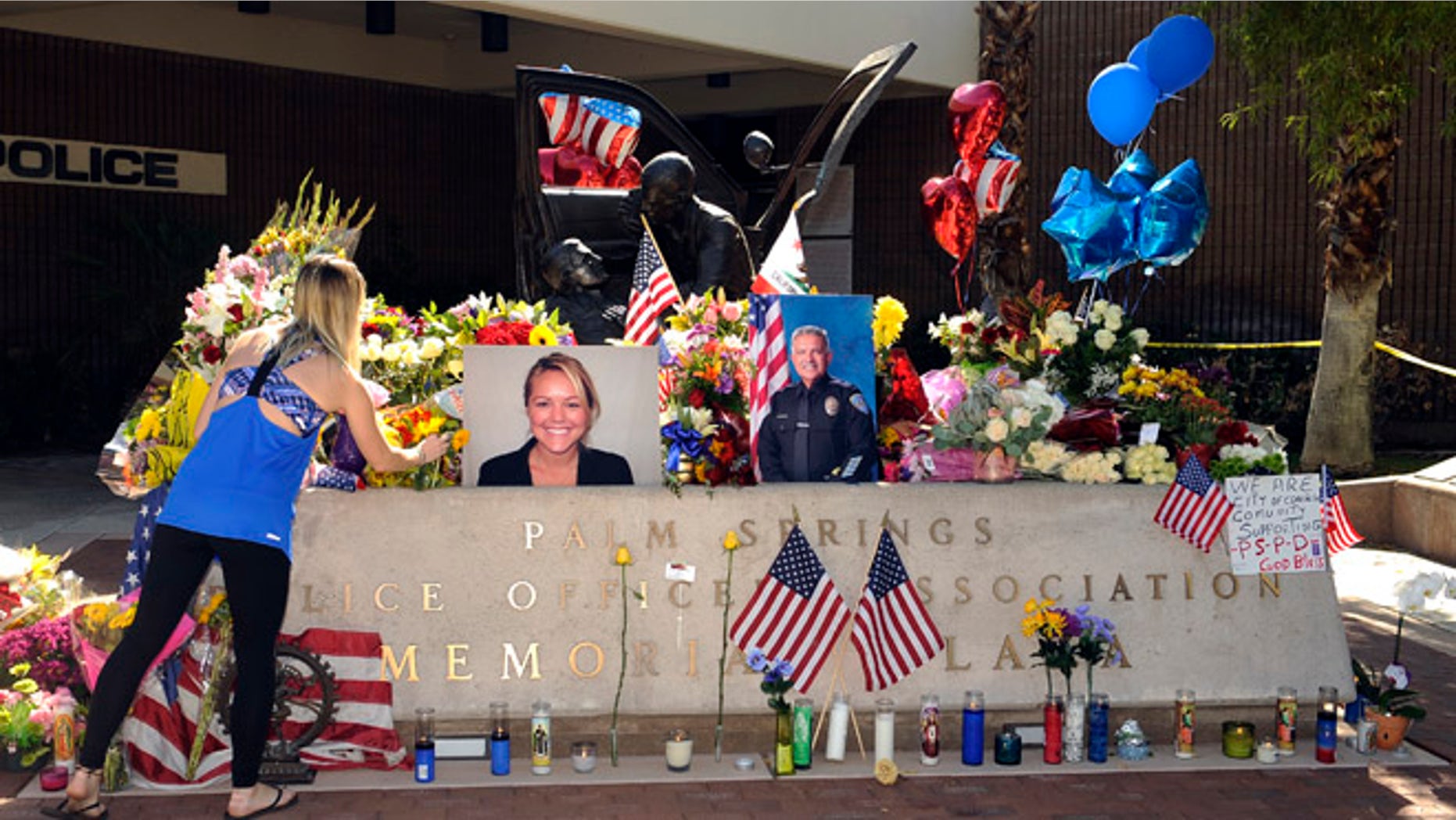 Kimberleigh Funkey, from Palm Springs, Calif., lays flowers by photos of slain Palm Springs police officers Lesley Zerebny and Jose "Gil" Gilbert Vega, in front of the police station in Palm Springs, Calif., Sunday, Oct. 9, 2016. (AP Photo/Rodrigo Peña)
